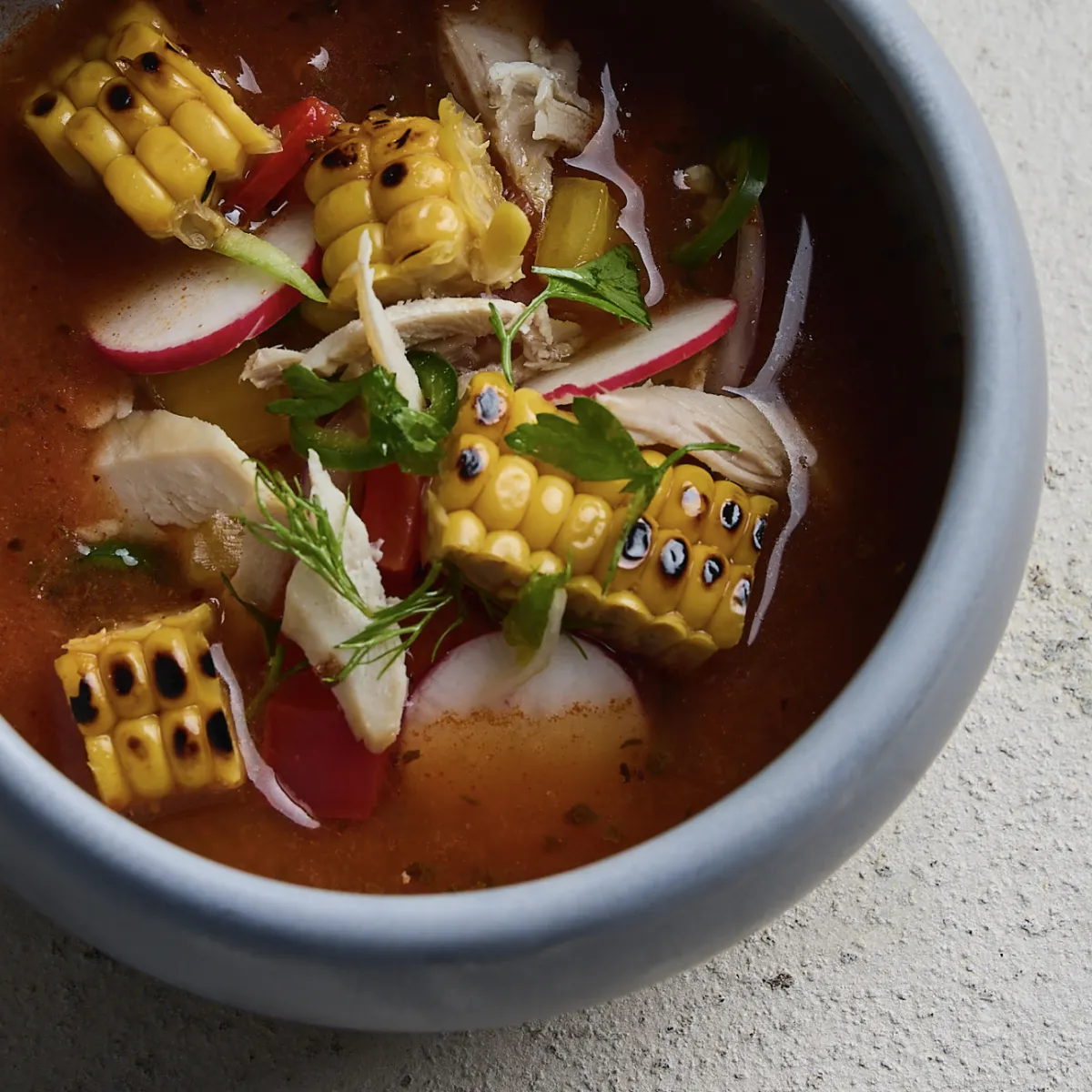 A charred corn broth with radishes and coriander