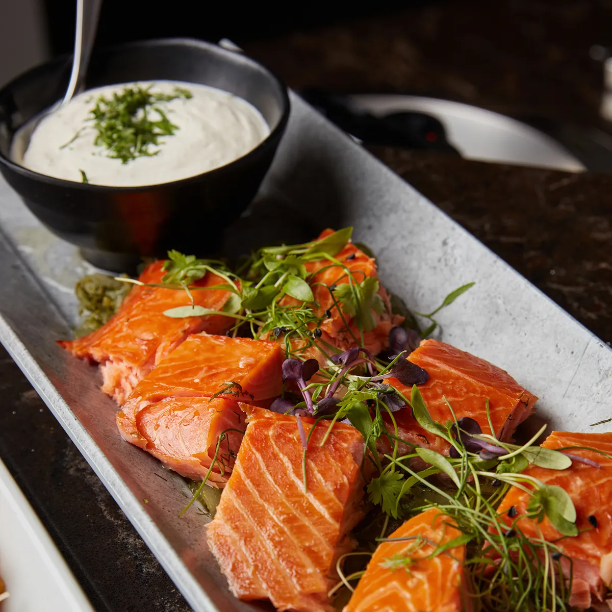 A plate of salmon with garnish and a sauce.