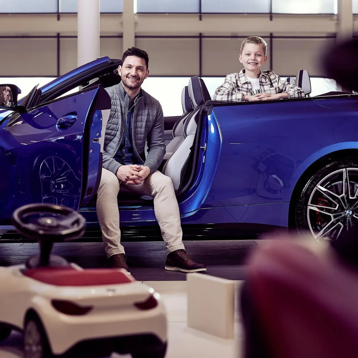 Father and son sat in a car smiling