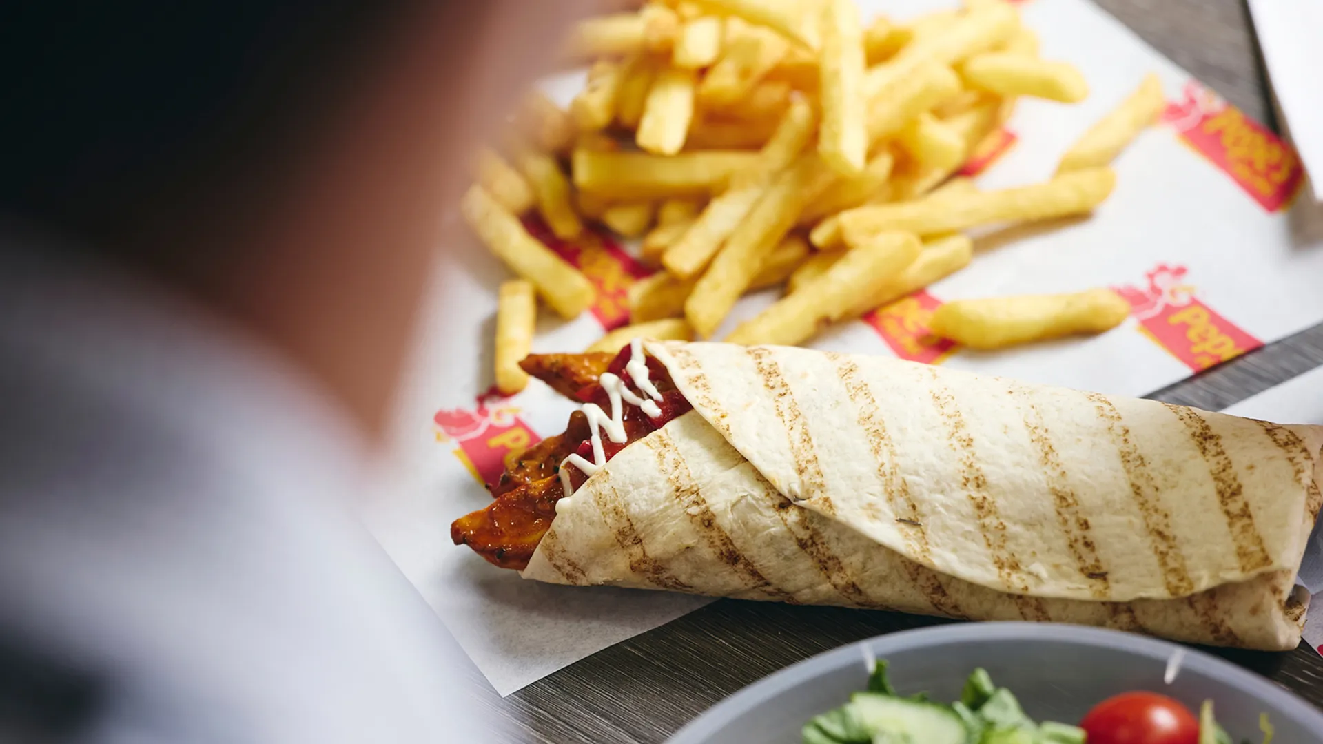 Pepe's chicken wrap on a table with chips and salad