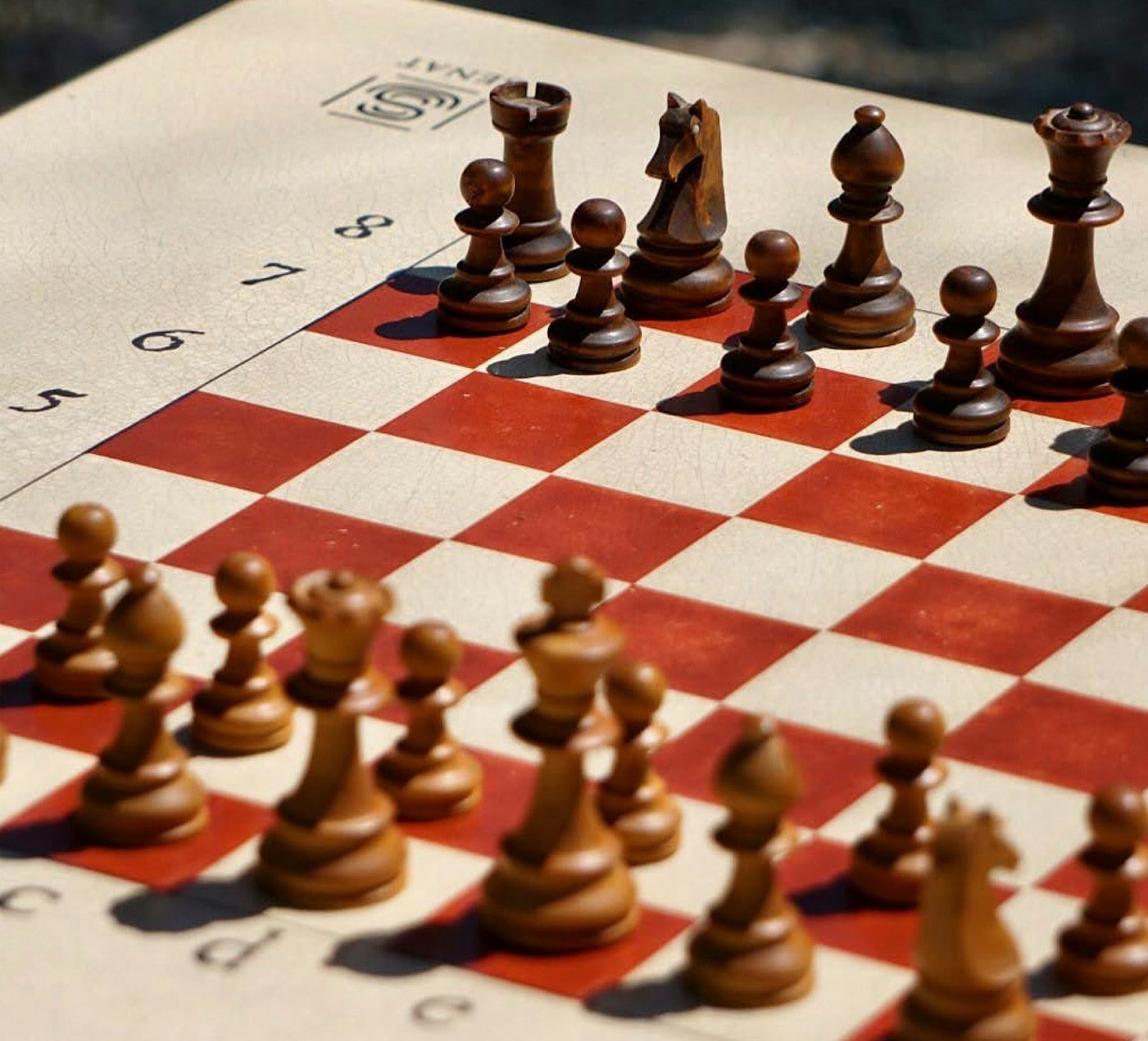 A chessboard set up mid-game with wooden chess pieces arranged in strategic positions.