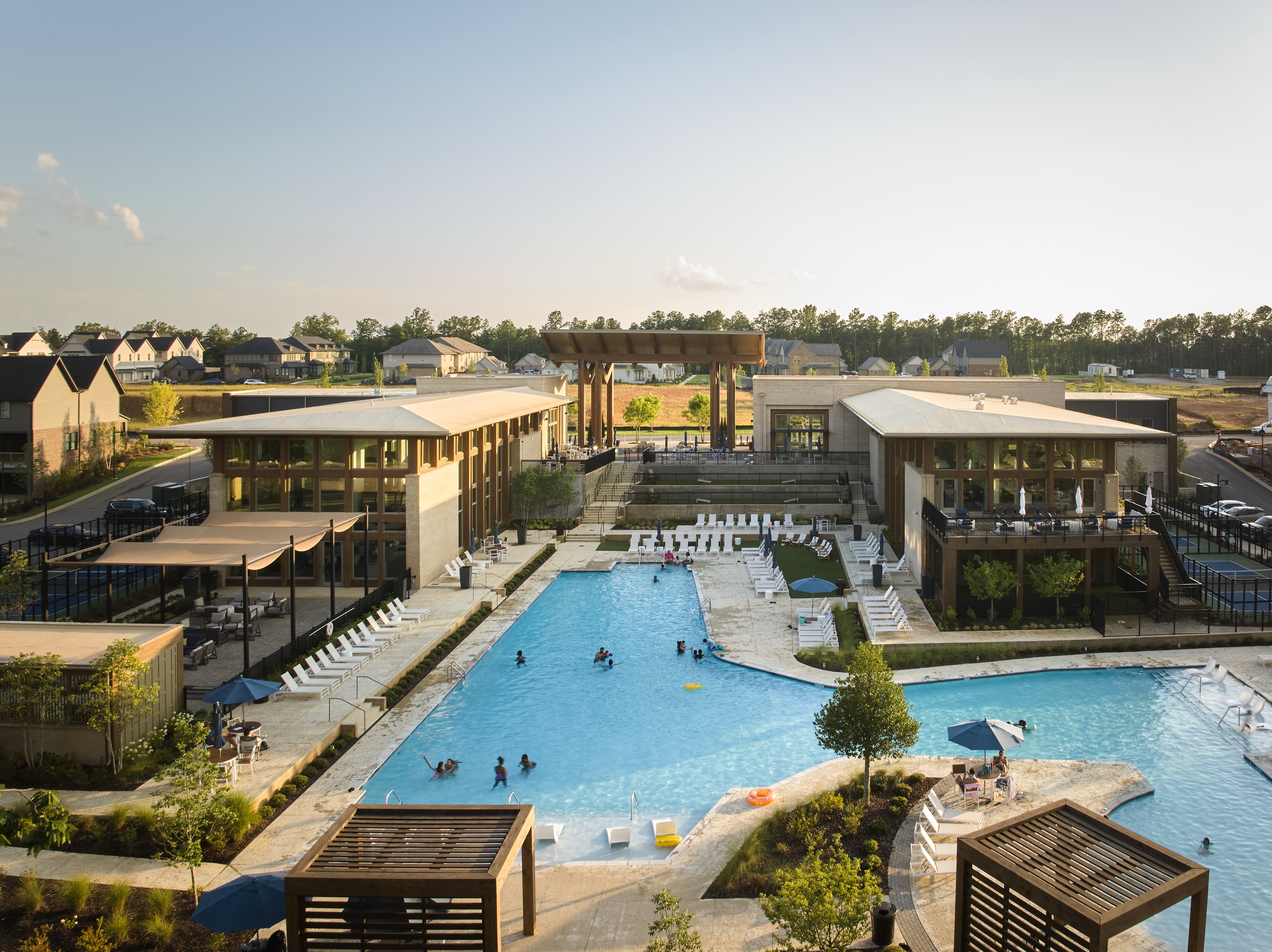 Swimmers in the Everlee Clubhouse pool with the amenity buildings behind, photographed by Omar Mohammad Studio