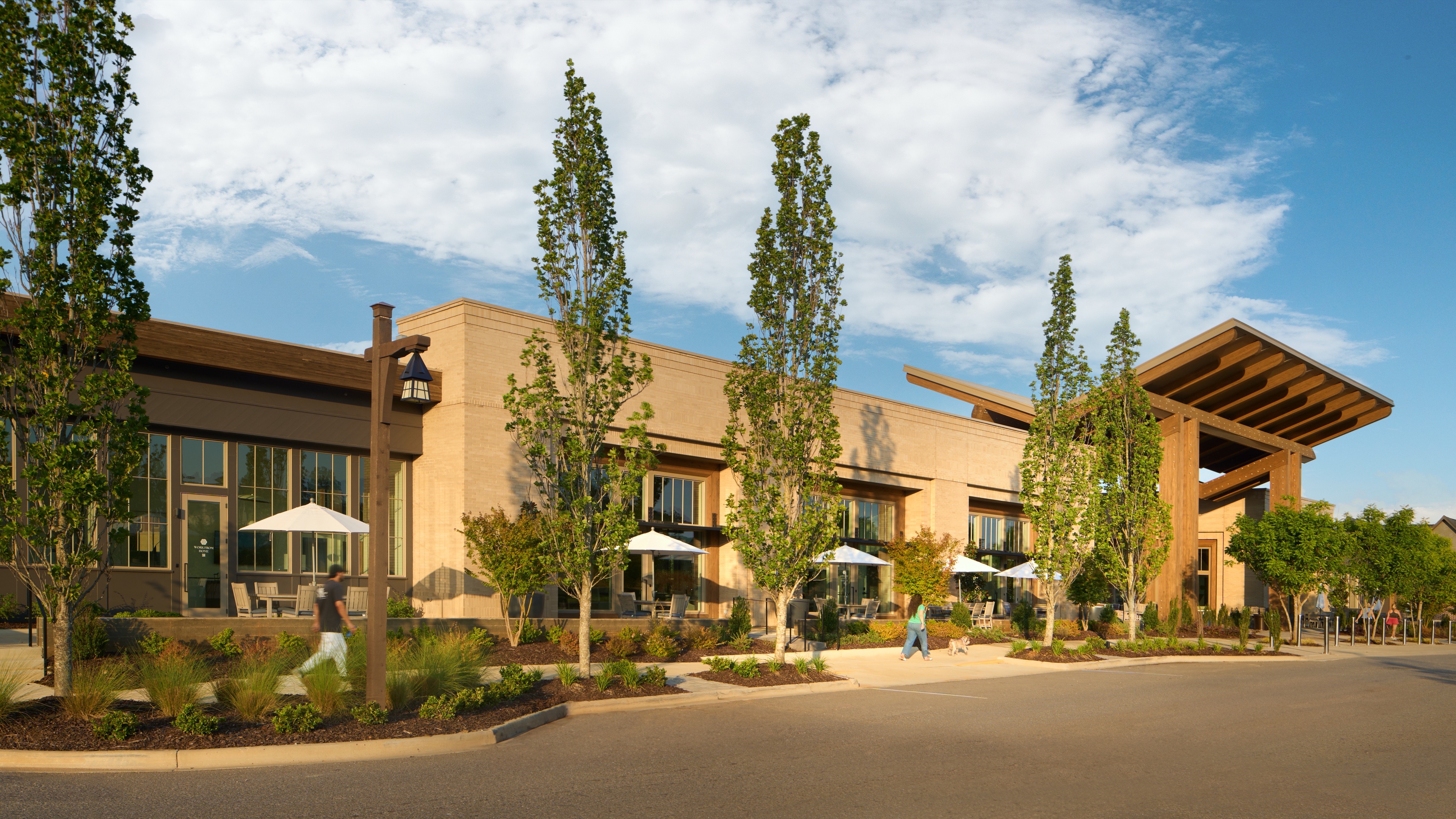 Everlee Clubhouse street elevation in stone and timber with young poplars along the drive, photographed by Omar Mohammad Studio