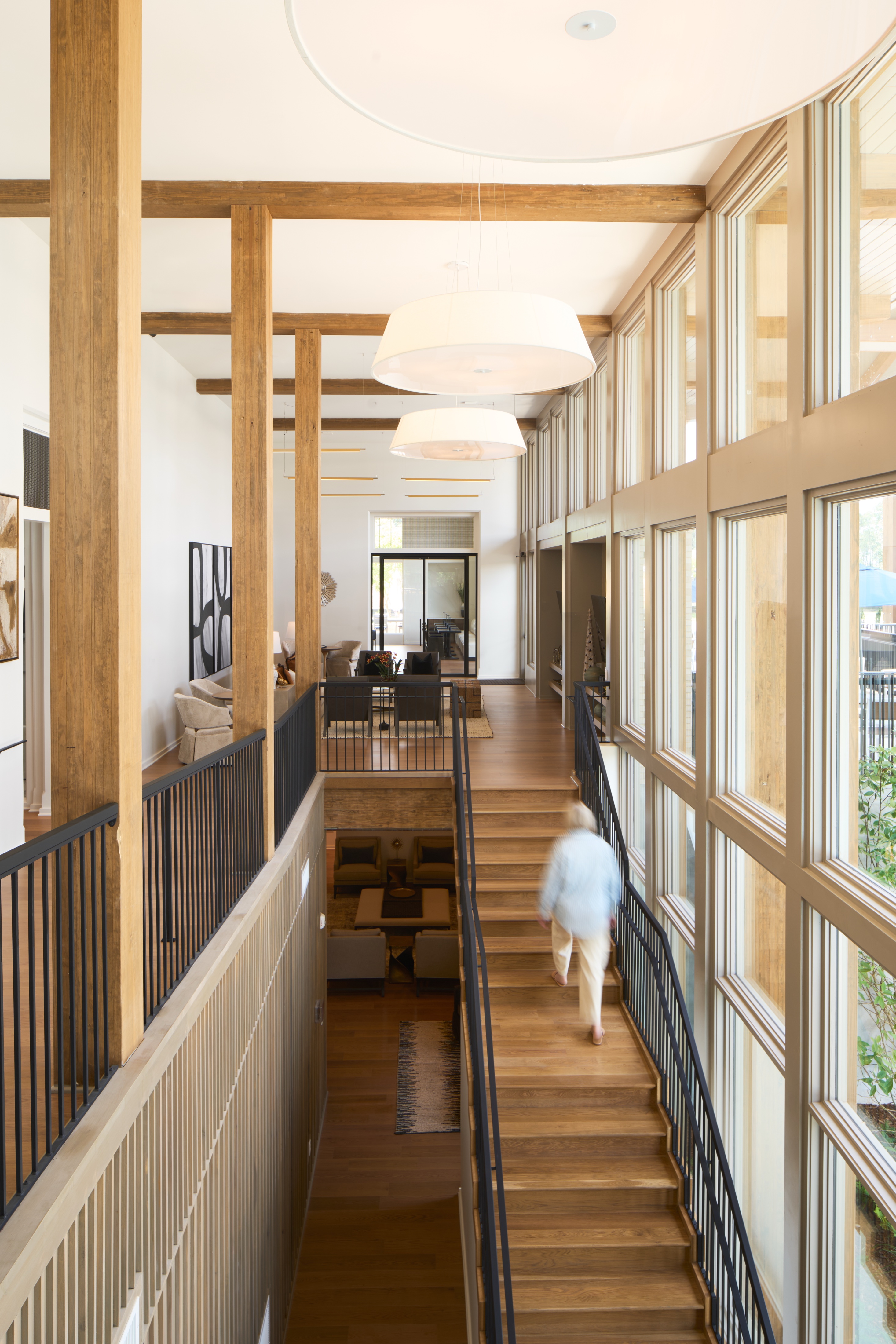 Timber framed mezzanine walkway and stair at the Everlee Clubhouse lit by a wall of windows, architectural photography by Omar Mohammad Studio
