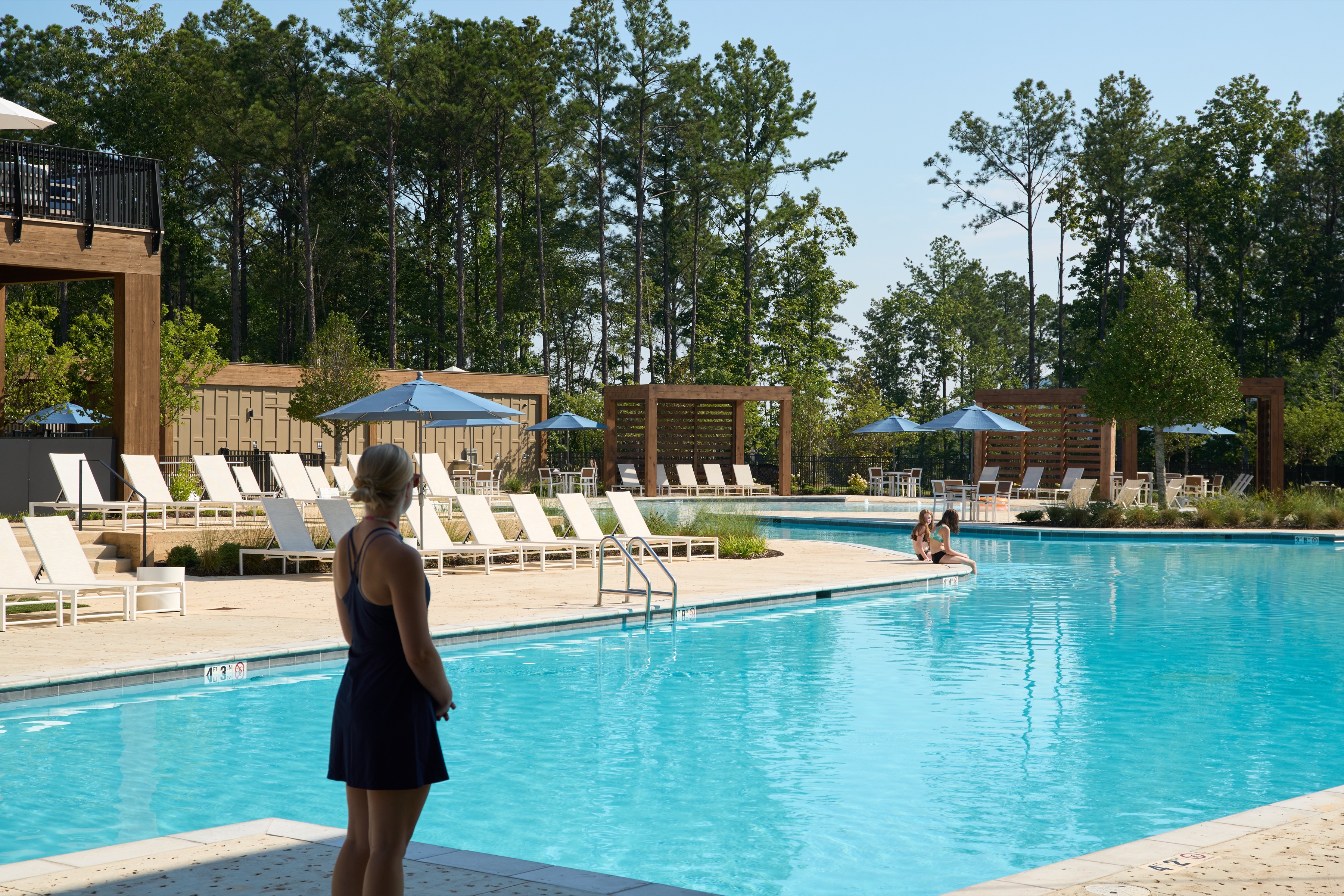Swimmer and loungers at the Everlee Clubhouse pool with pines beyond, architectural photography by Omar Mohammad Studio