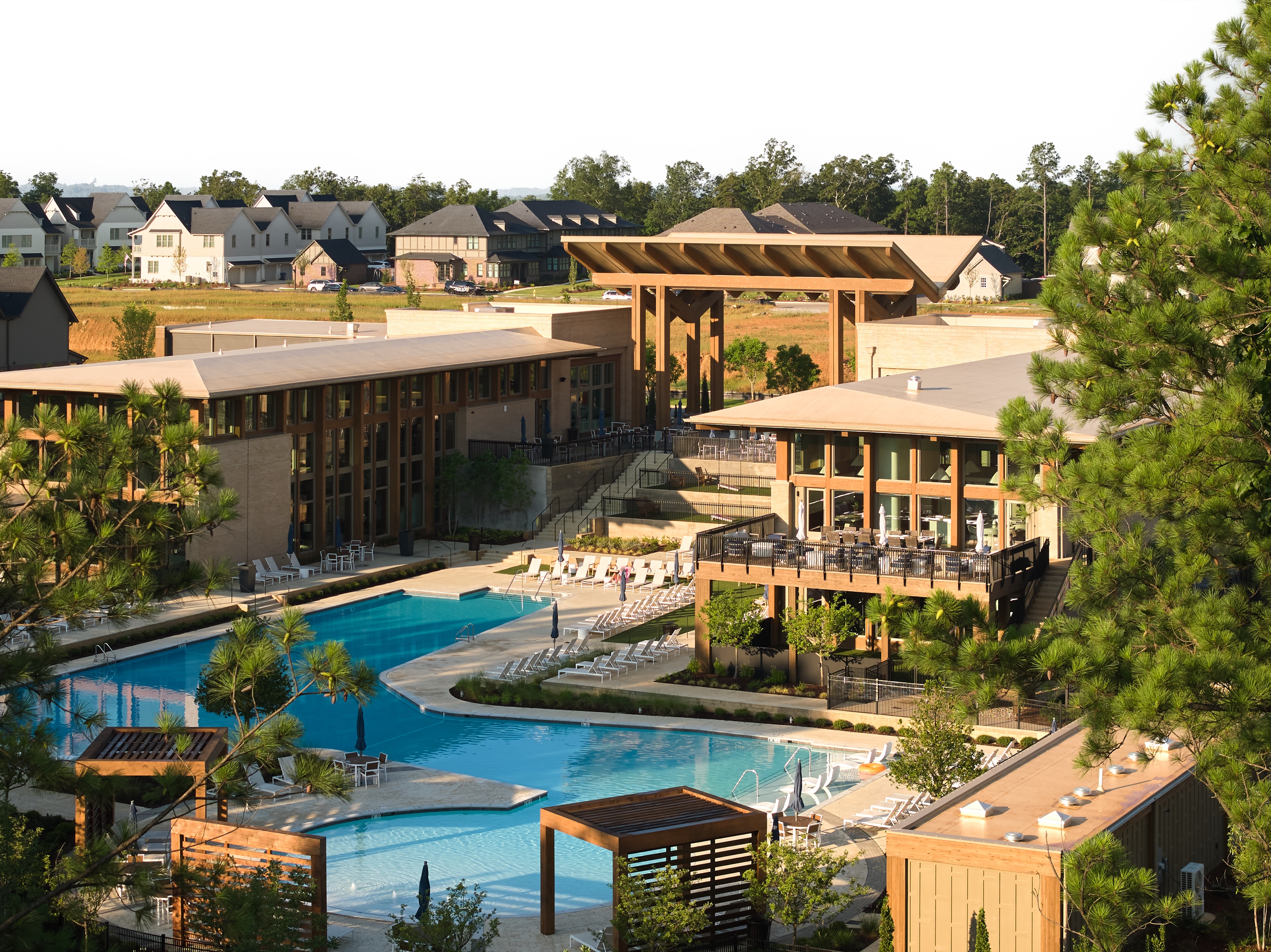 Everlee Clubhouse amenity buildings rising above the pool terrace and framed by pines, photographed by Omar Mohammad Studio