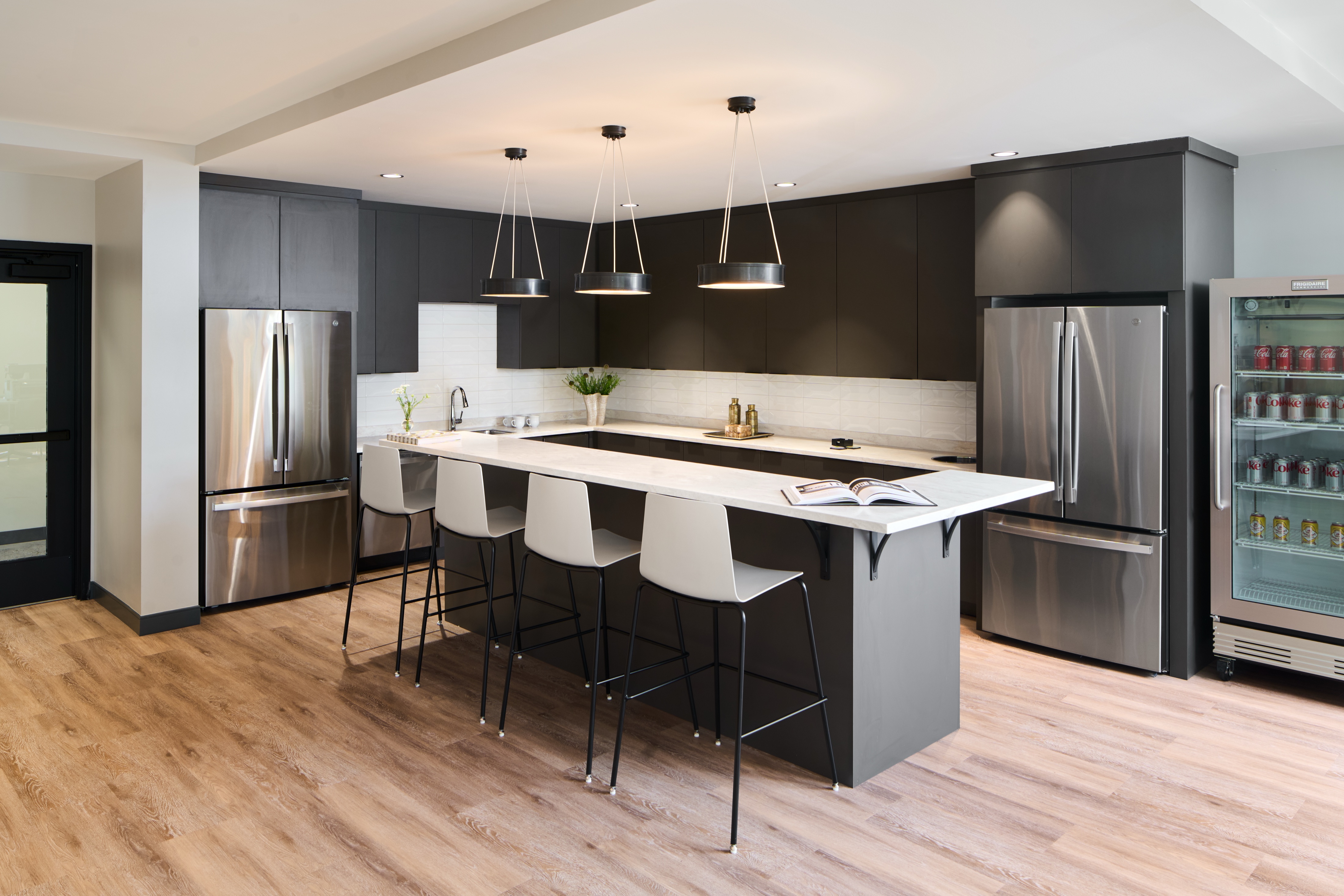 Staff pantry with dark cabinetry, waterfall island and pendant lights, workplace photography by Omar Mohammad Studio