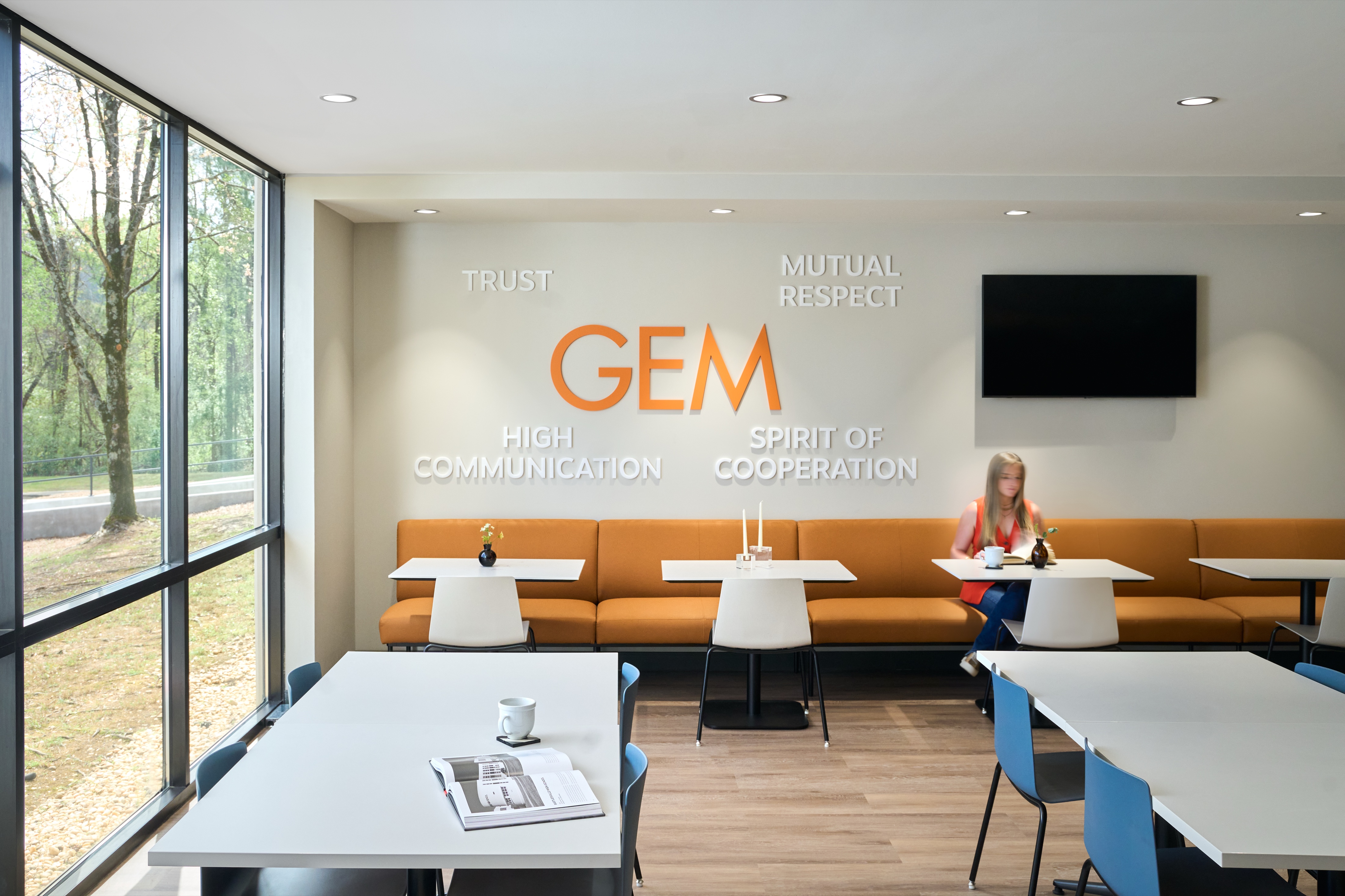 GEM collaboration area with orange banquette seating and values wall graphic, workplace photography by Omar Mohammad Studio