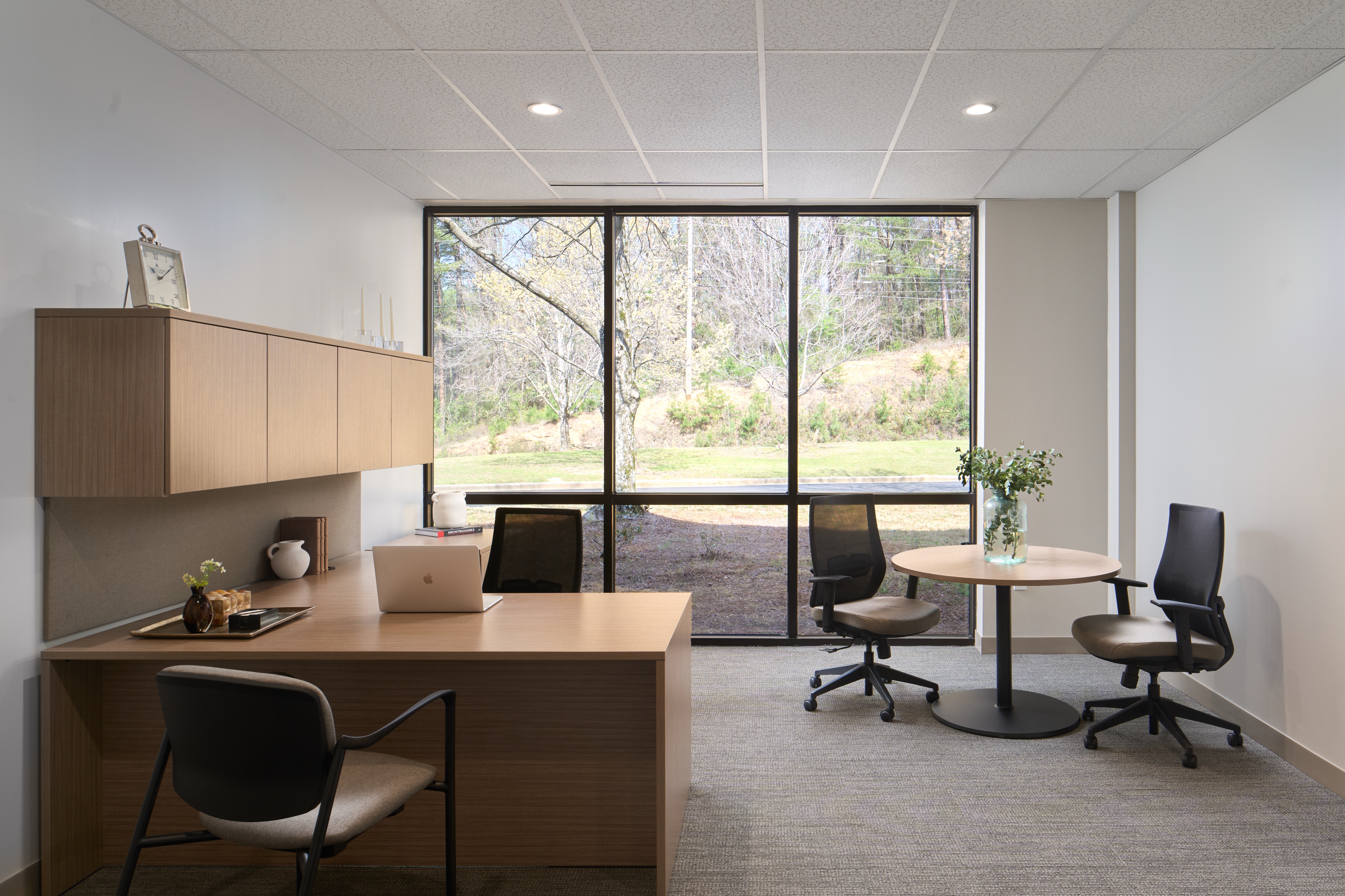 Private office with built in casework and a round meeting table at a full height window, workplace photography by Omar Mohammad Studio