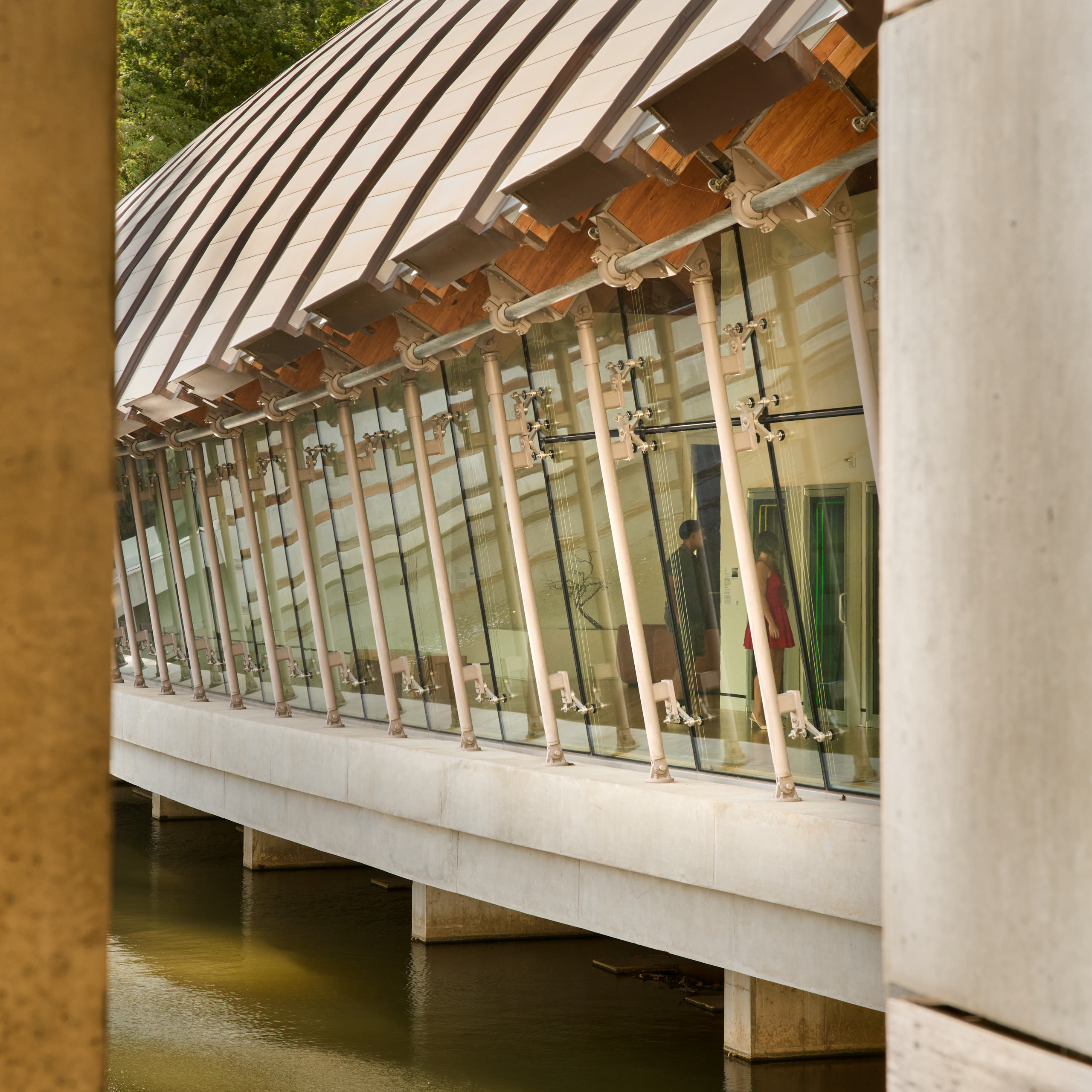 Bridge gallery facade on concrete piers over the pond at Crystal Bridges Museum of American Art, architectural photography by Omar Mohammad Studio