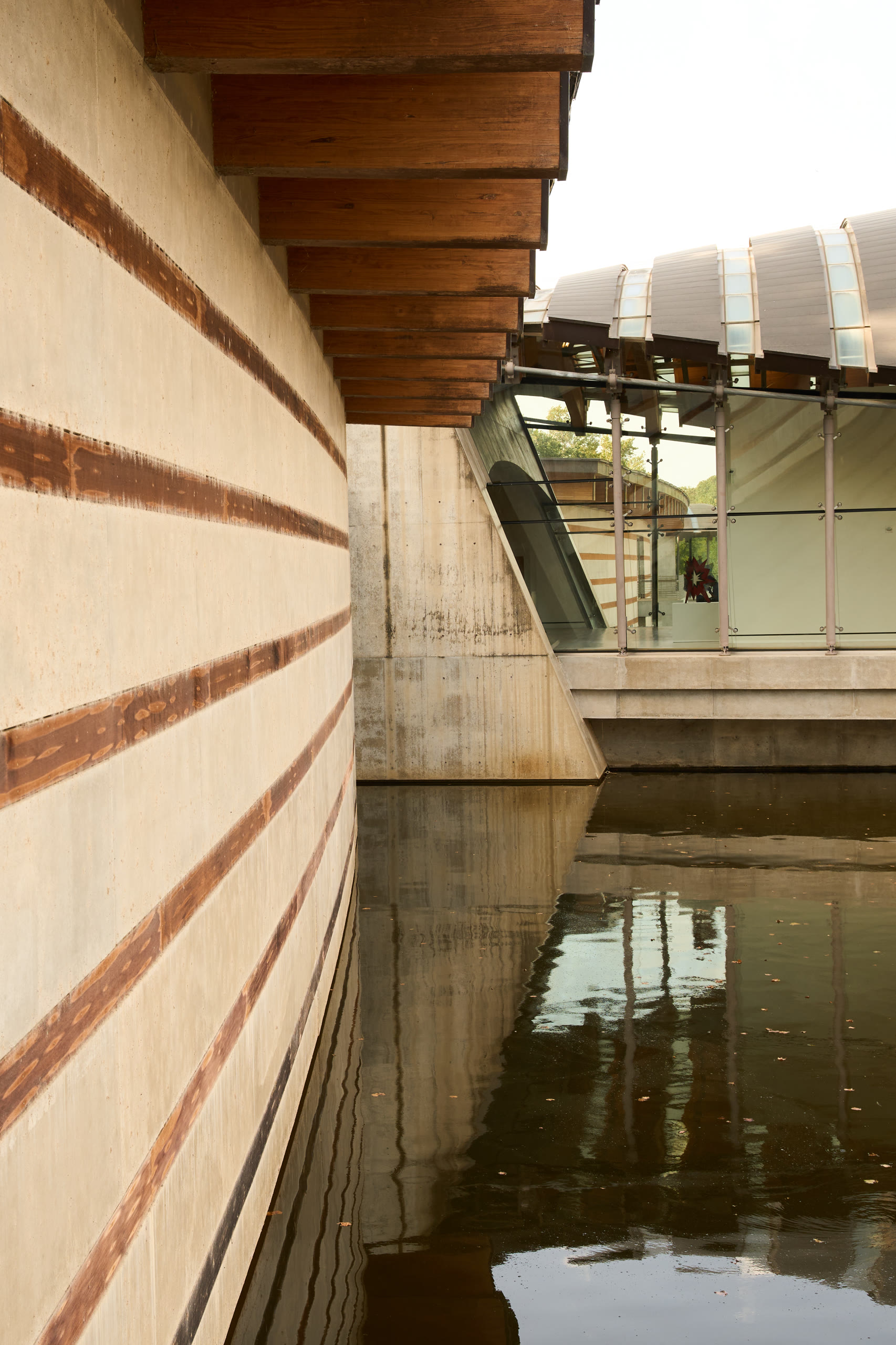 Banded concrete wall reflected in the pond at Crystal Bridges Museum of American Art, architectural photography by Omar Mohammad Studio