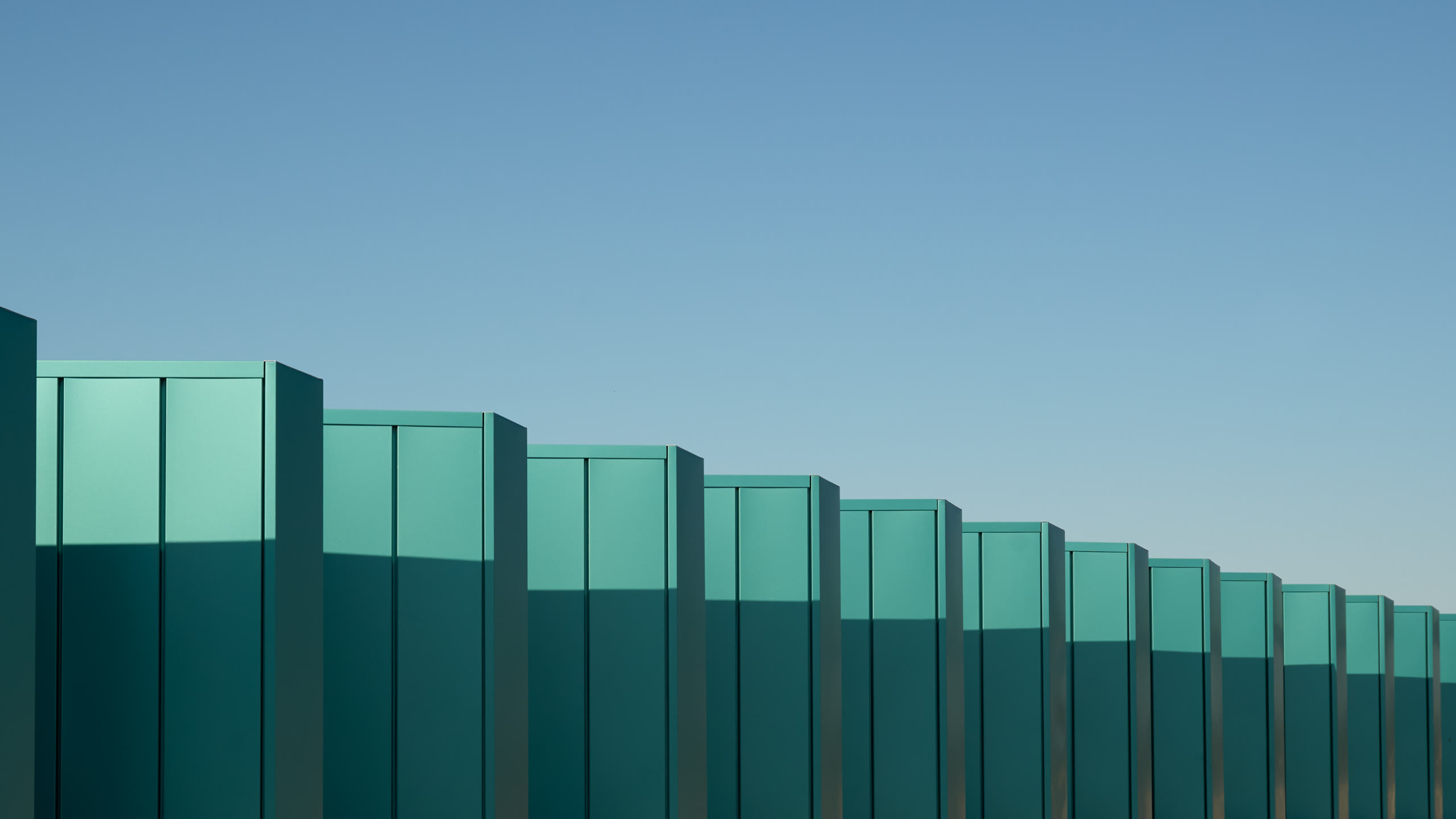 Row of teal fins against a clear sky at the Crystal Bridges parking deck, architectural photography by Omar Mohammad Studio