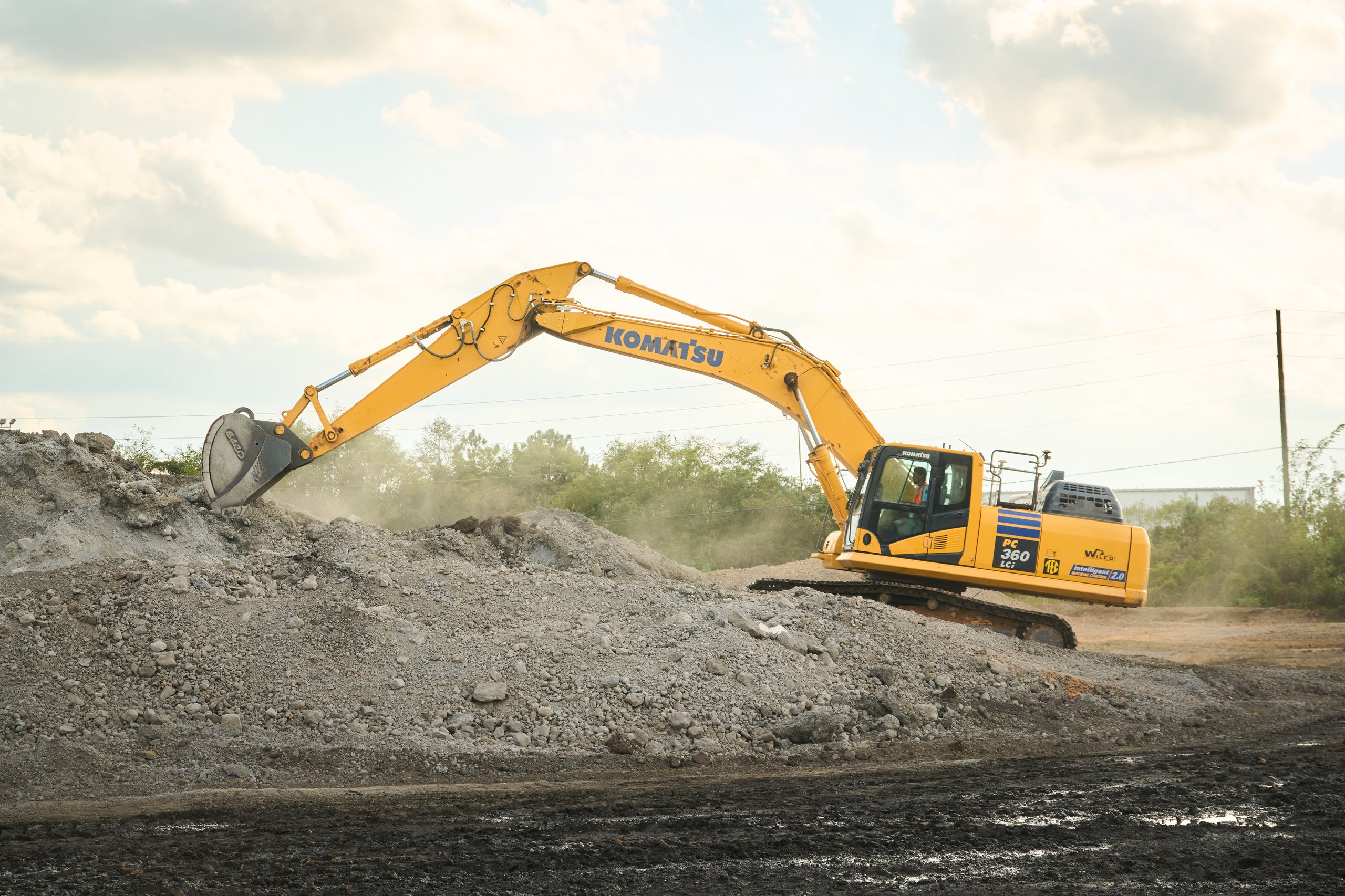 Excavator working a stone stockpile at the Coalburg site for Cooper Construction, photographed by Omar Mohammad Studio