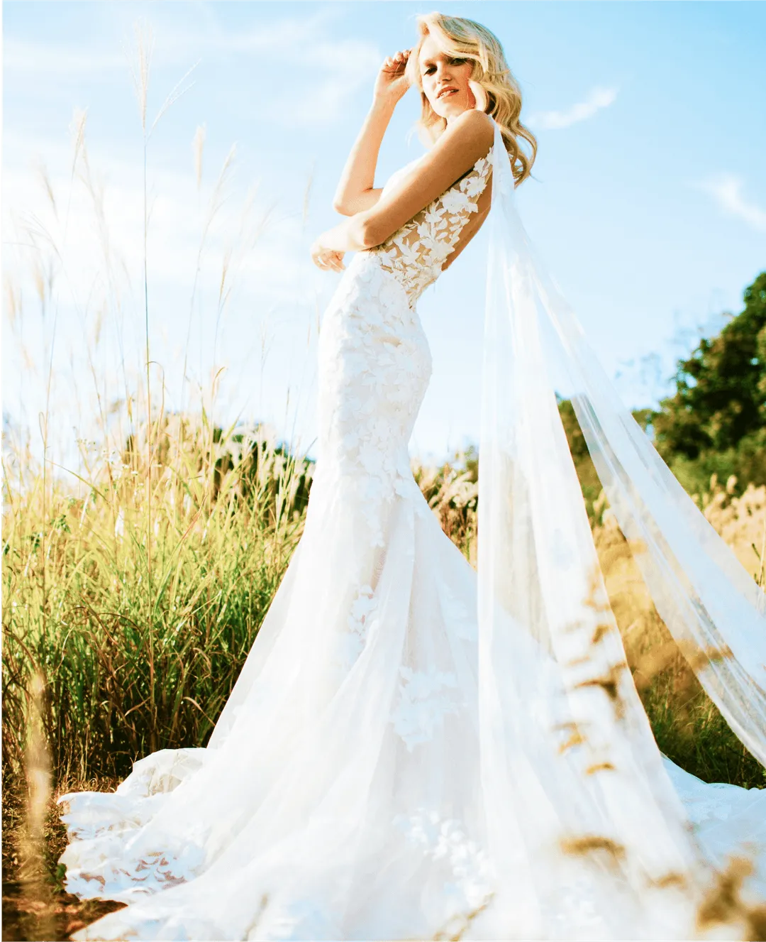 A beautiful photo of a girl in a wedding dress outside with trees and green grass