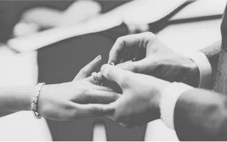Black and white photo of a man's hands putting a wedding ring on a woman's hand