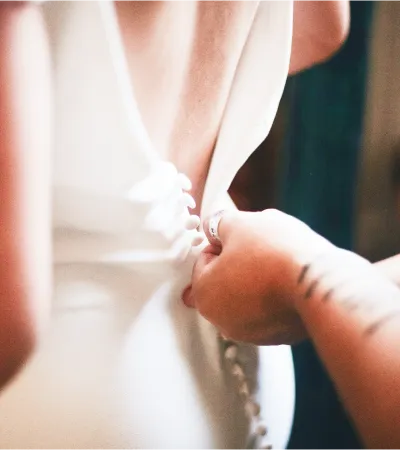 A woman's wedding dress is fastened from the back