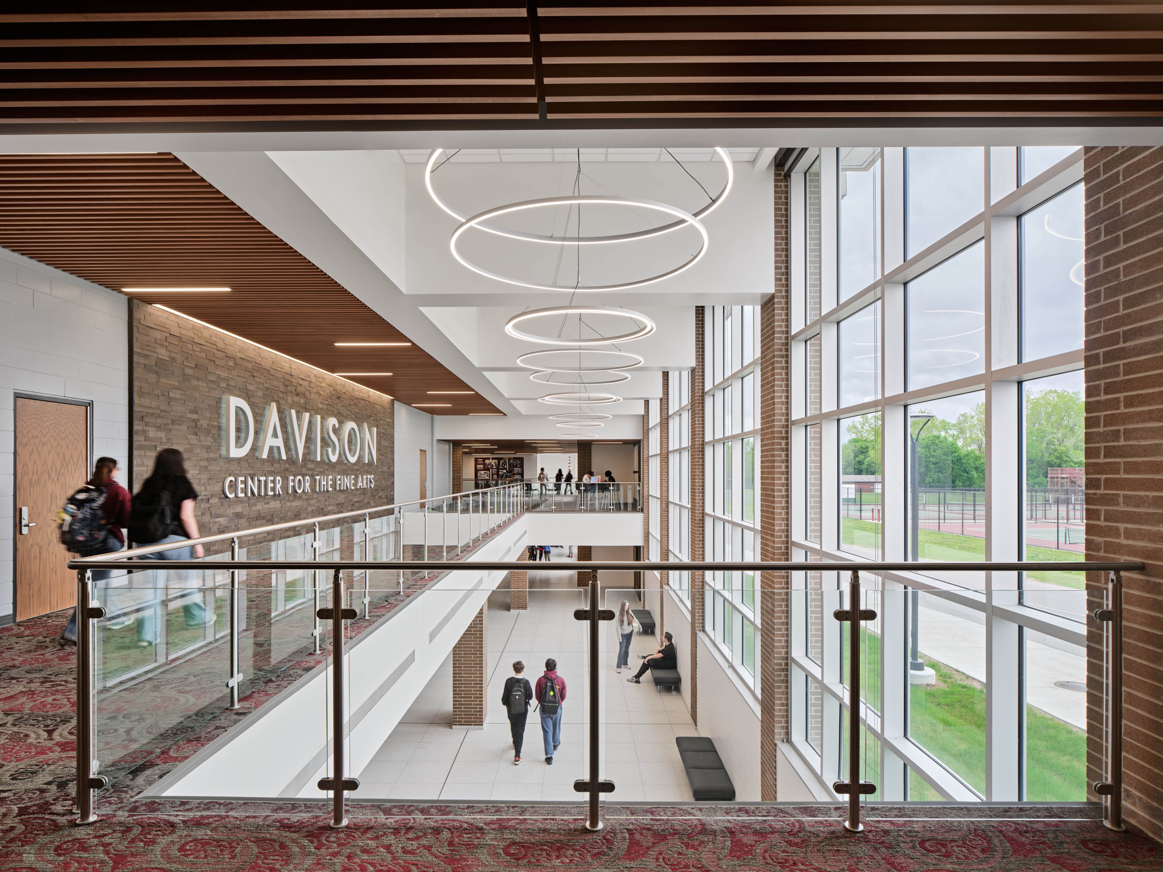 Interior view of Davison Center for the Fine Arts with students walking on both floors, large windows on the right, and circular ceiling lights.