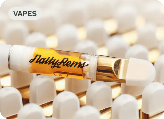 Close-up of a NattyRems vape cartridge with golden liquid, surrounded by white vape cartridge tips.
