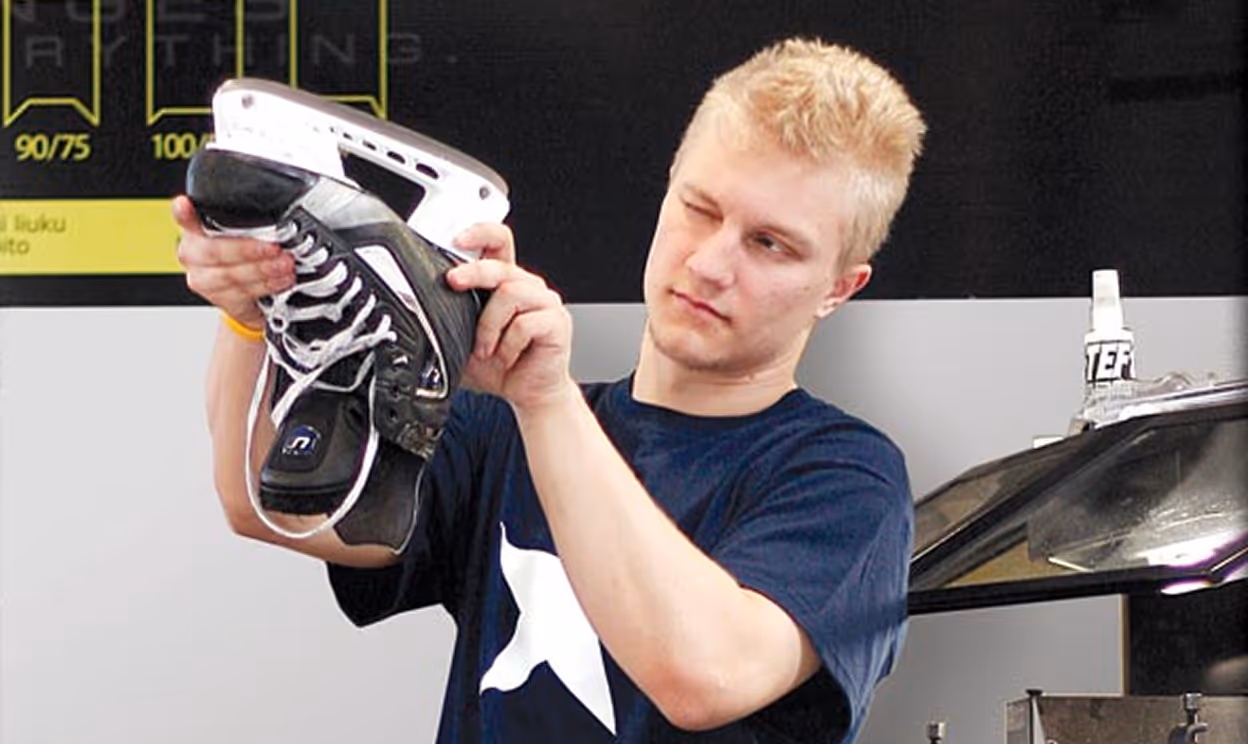 Nuori mies tarkistaa jääkiekkoluistimet ja tarkastelee terää.