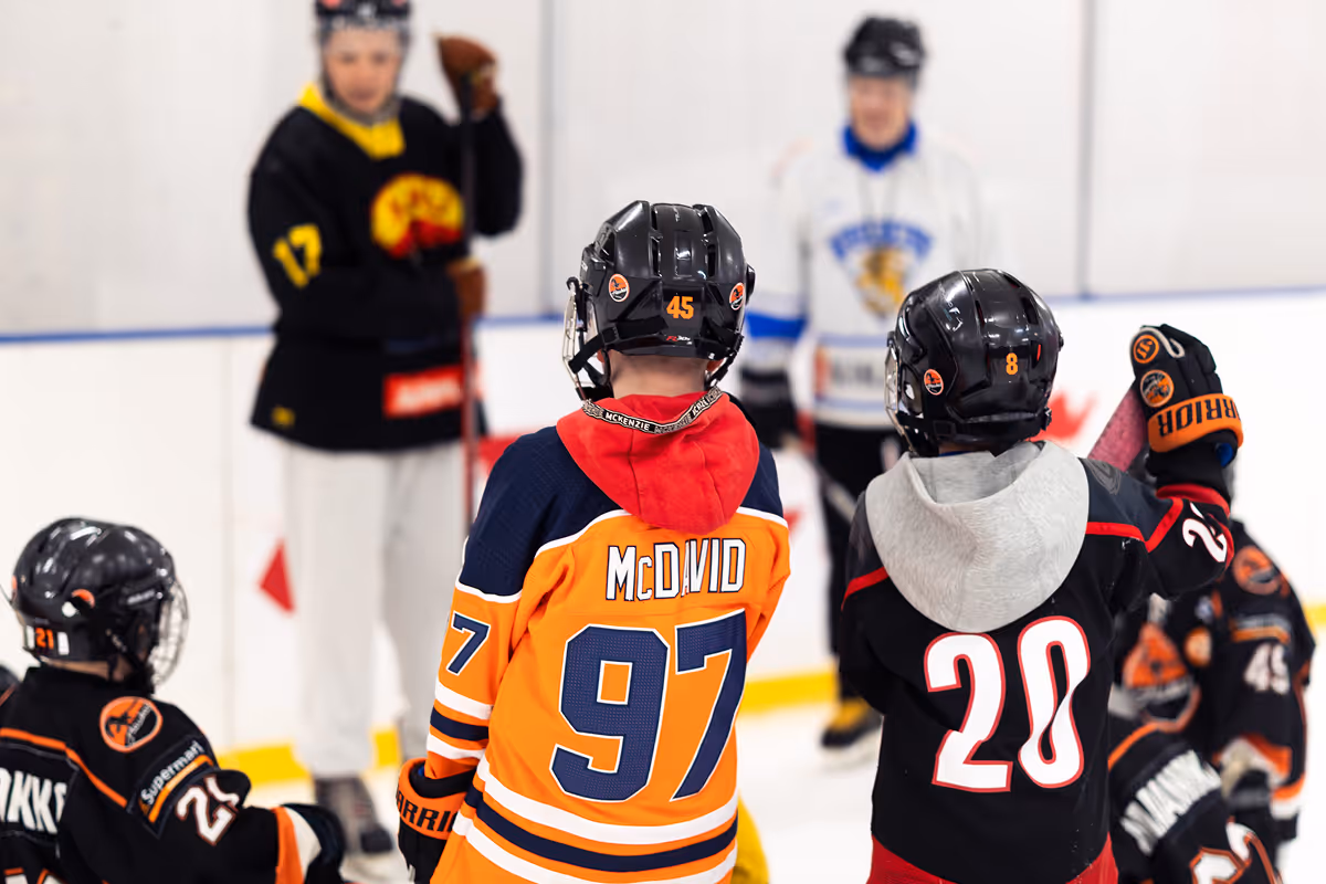 Lapsia jääkiekkovarusteissa kaukalossa, näkyvissä McDavid-pelipaita numerolla 97.