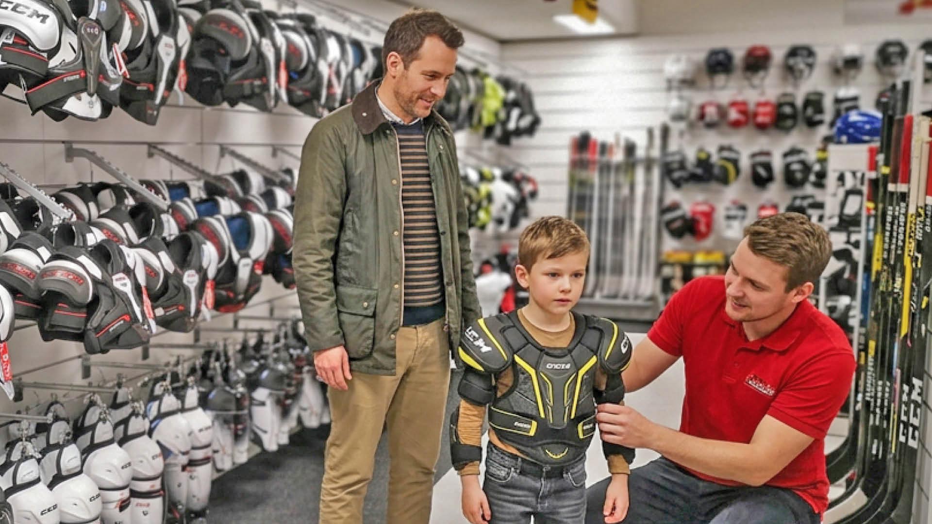 Isä lapsen kanssa sovittamassa jääkiekkovarusteita Hockey Base myymälässä