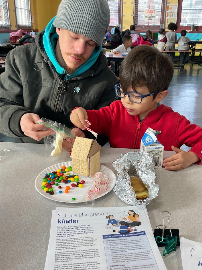 Adult helping child build a craft house