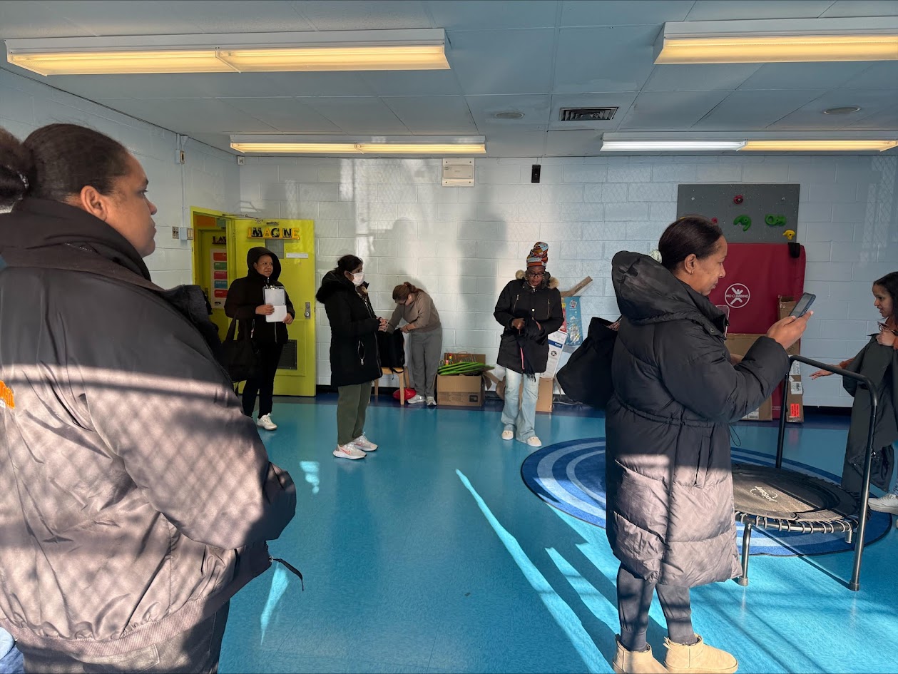 People gathered inside a school hallway or room, some standing and talking during an indoor event.