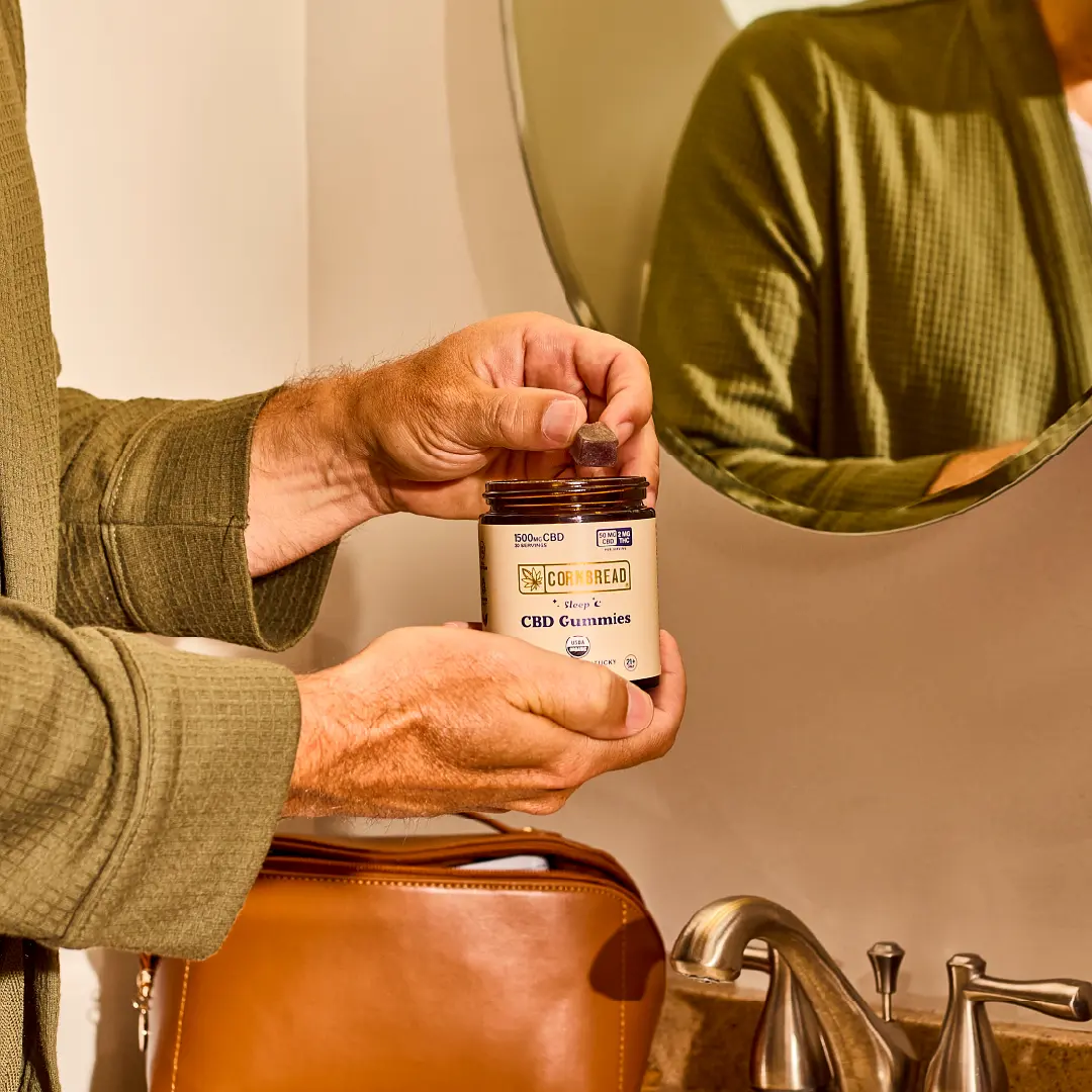 Man in a bathrobe holding a bottle of gummies
