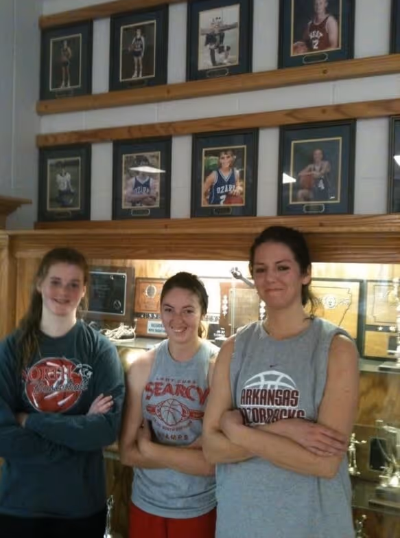 Arielle Butler (middle) stands underneath a photo of Kendra Bailey, accompanied by two friends during a fundraising event for Kendra's Voice