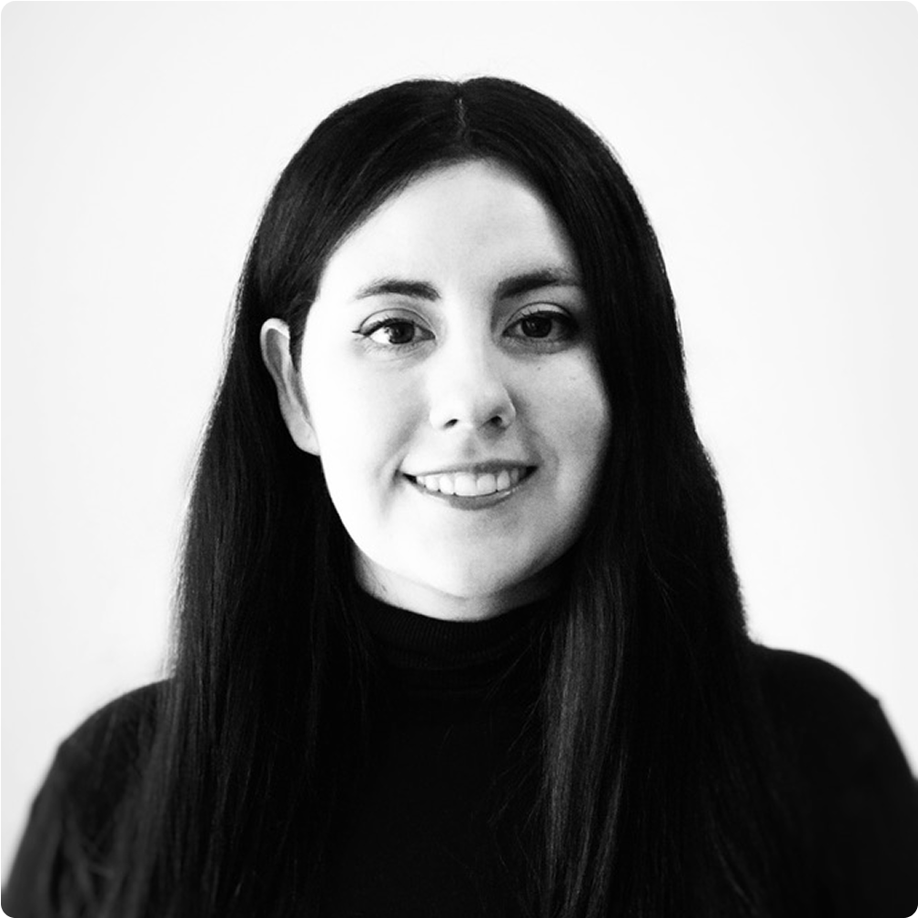 Black and white portrait of a young woman with long dark hair smiling, wearing a black turtleneck sweater.