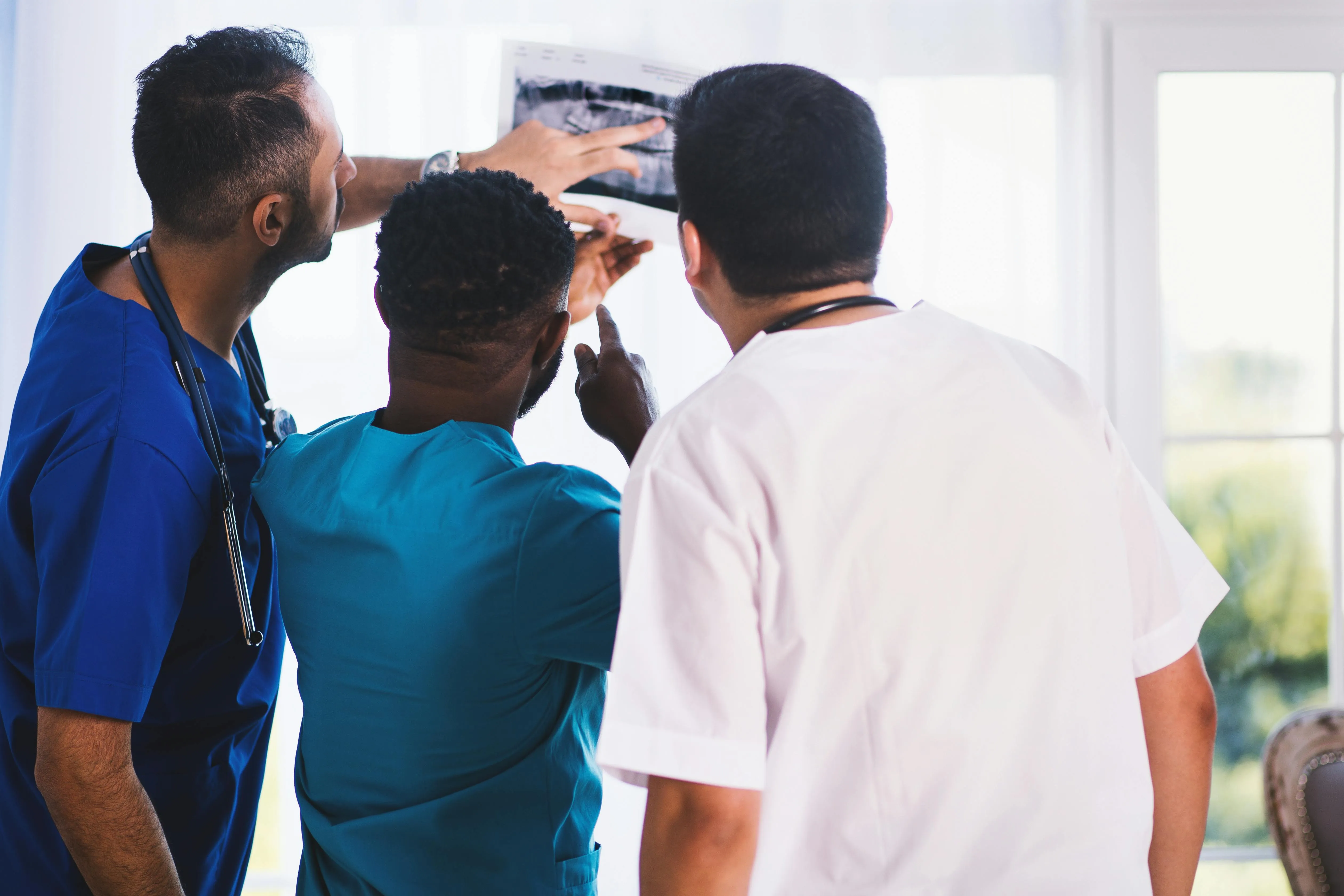 Three clinicians examining a dental radiograph together