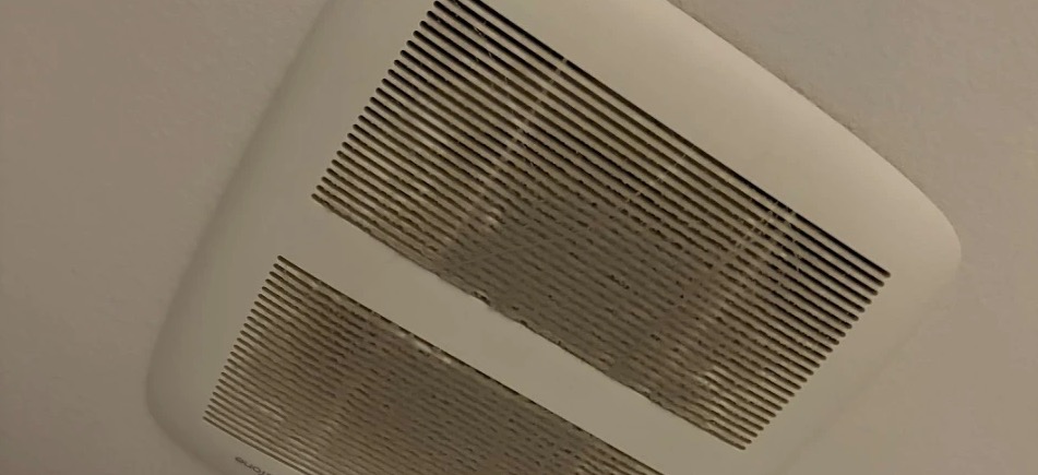 Dusty bathroom exhaust fan cover on a ceiling