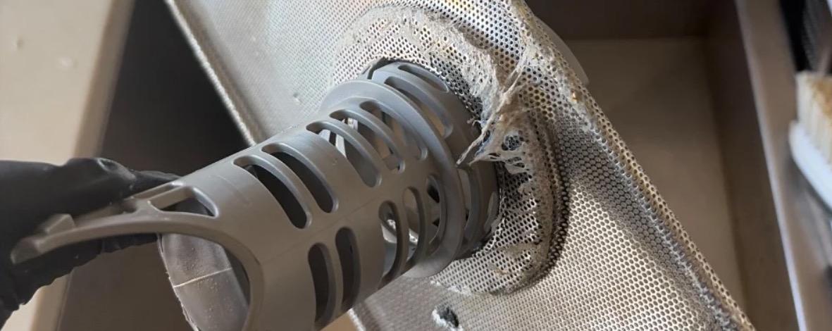 Dishwasher filter assembly with the cylindrical filter and mesh screen covered in debris