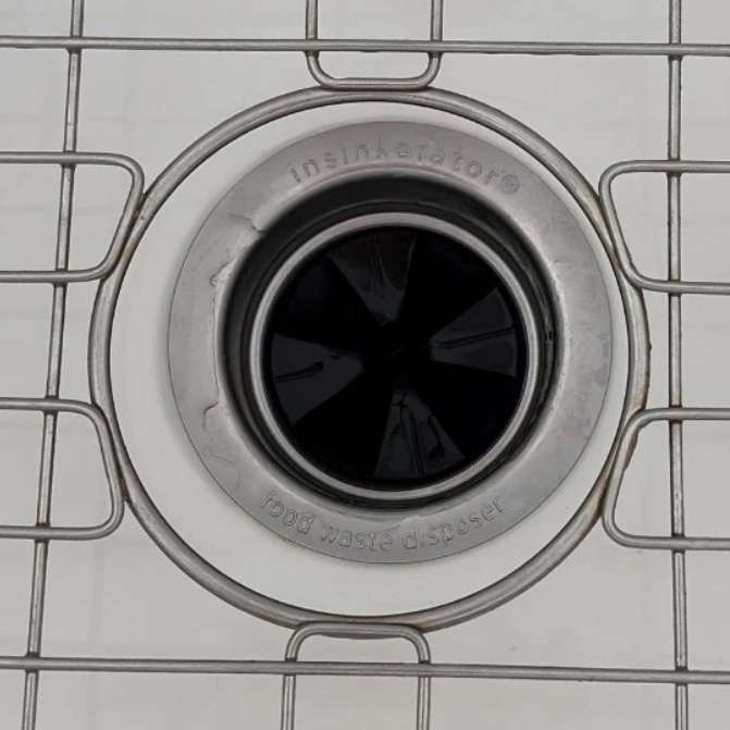 Garbage disposal opening with a rubber splash guard in a white kitchen sink