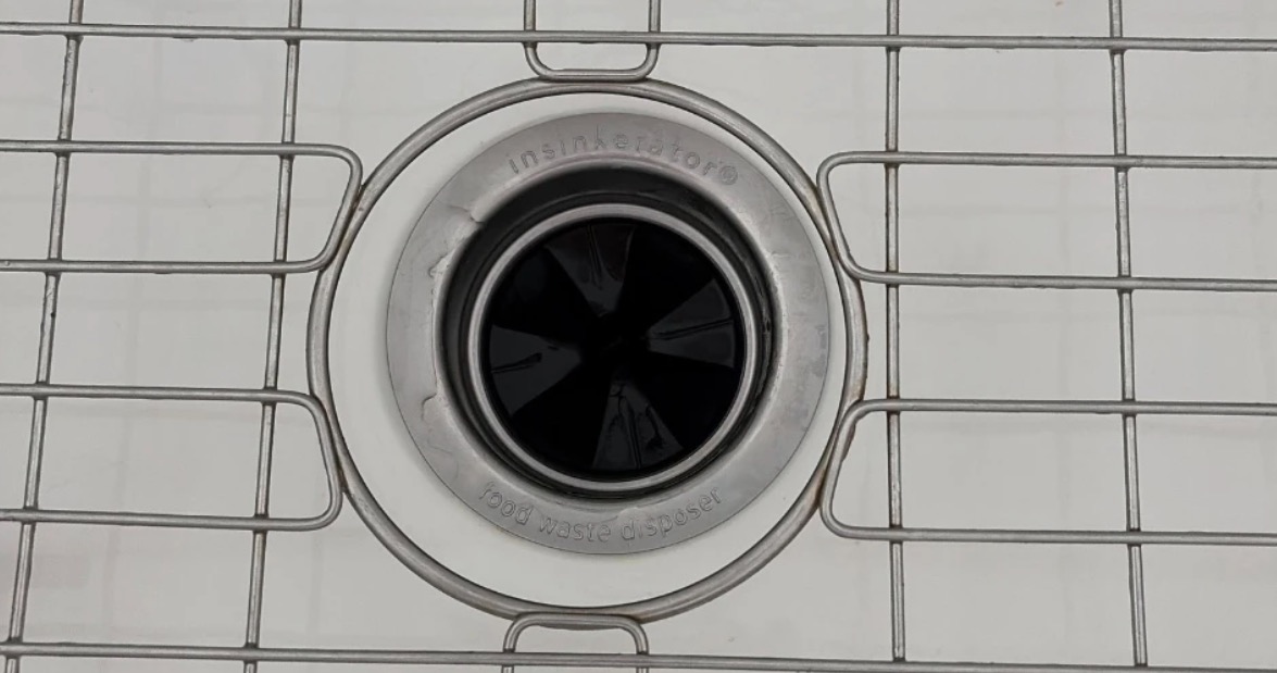 Garbage disposal opening with a rubber splash guard in a white kitchen sink