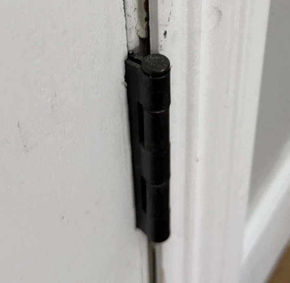Black hinge on a white interior door frame