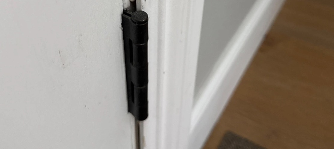Black hinge on a white interior door frame