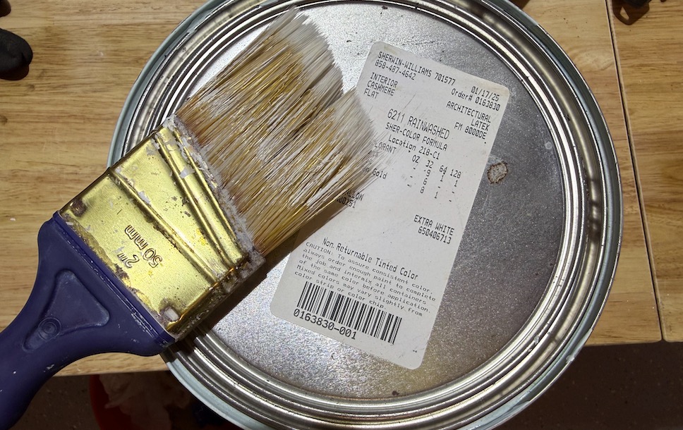 Paintbrush resting on an open can of interior wall paint