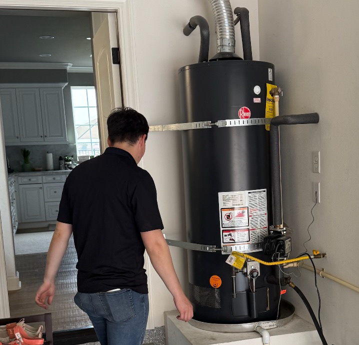 Livd handyman walking up to a gas tank water heater in a garage