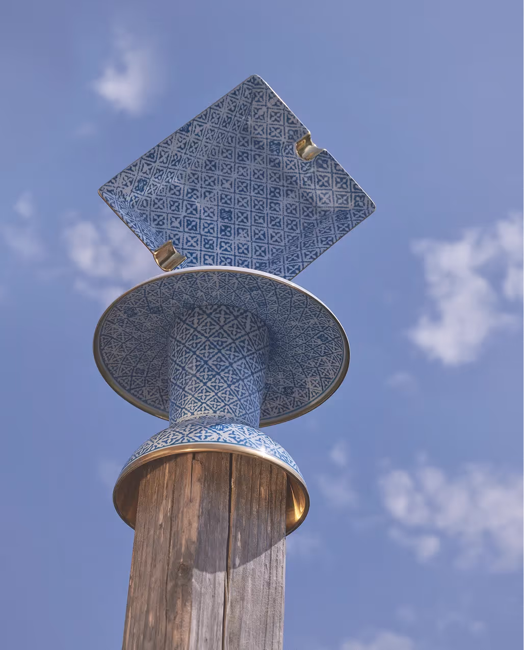 Gestapeltes Porzellan mit blauem geometrischem Muster auf einem Holzpfahl vor blauem Himmel