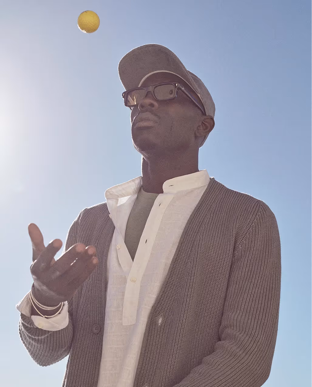 Mann mit Sonnenbrille und Strickjacke im warmen Licht als Teil der 04651 Sommerkollektion