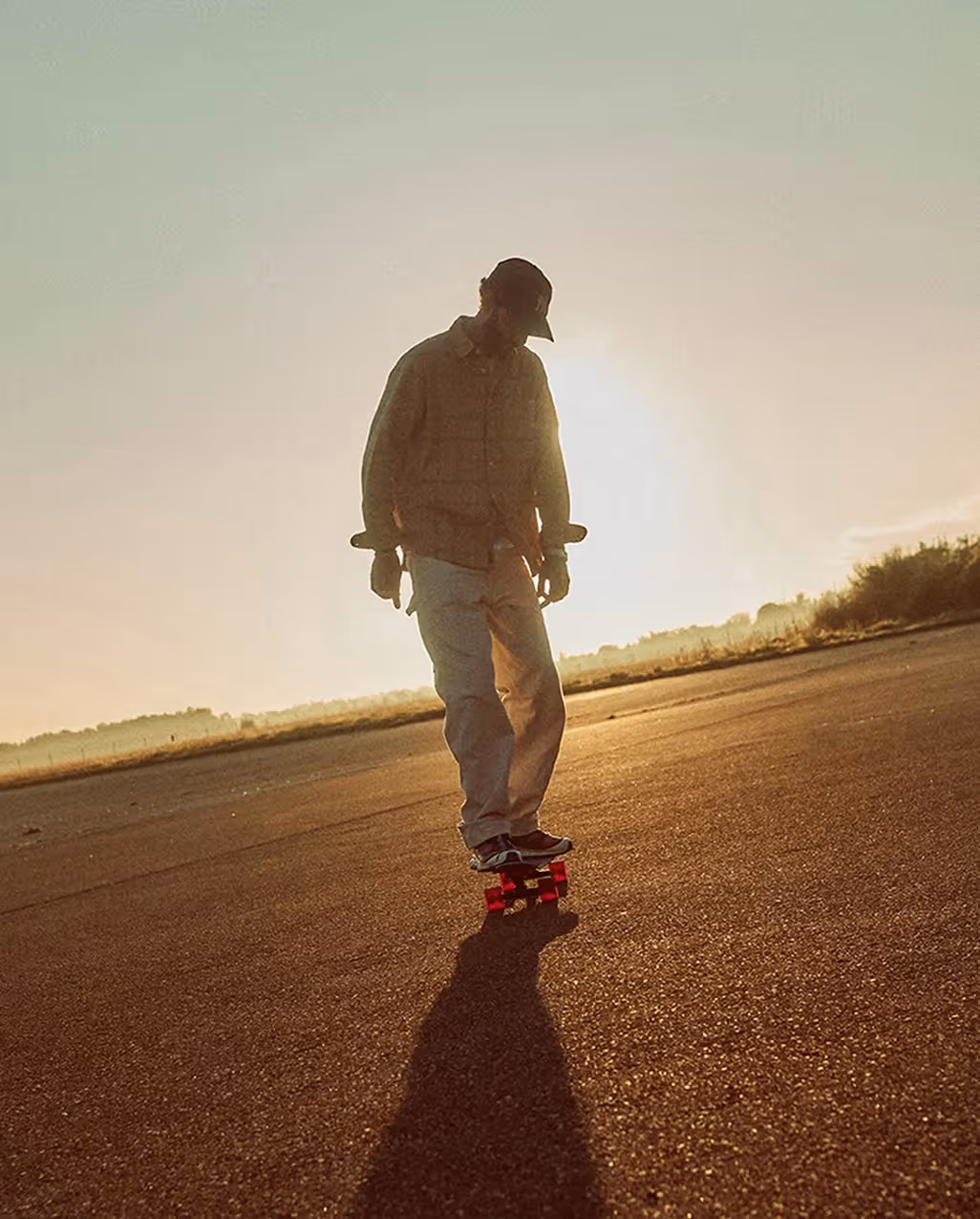 Skater fährt allein über eine leere Straße bei tief stehender Sonne für die BANZAI Kampagne
