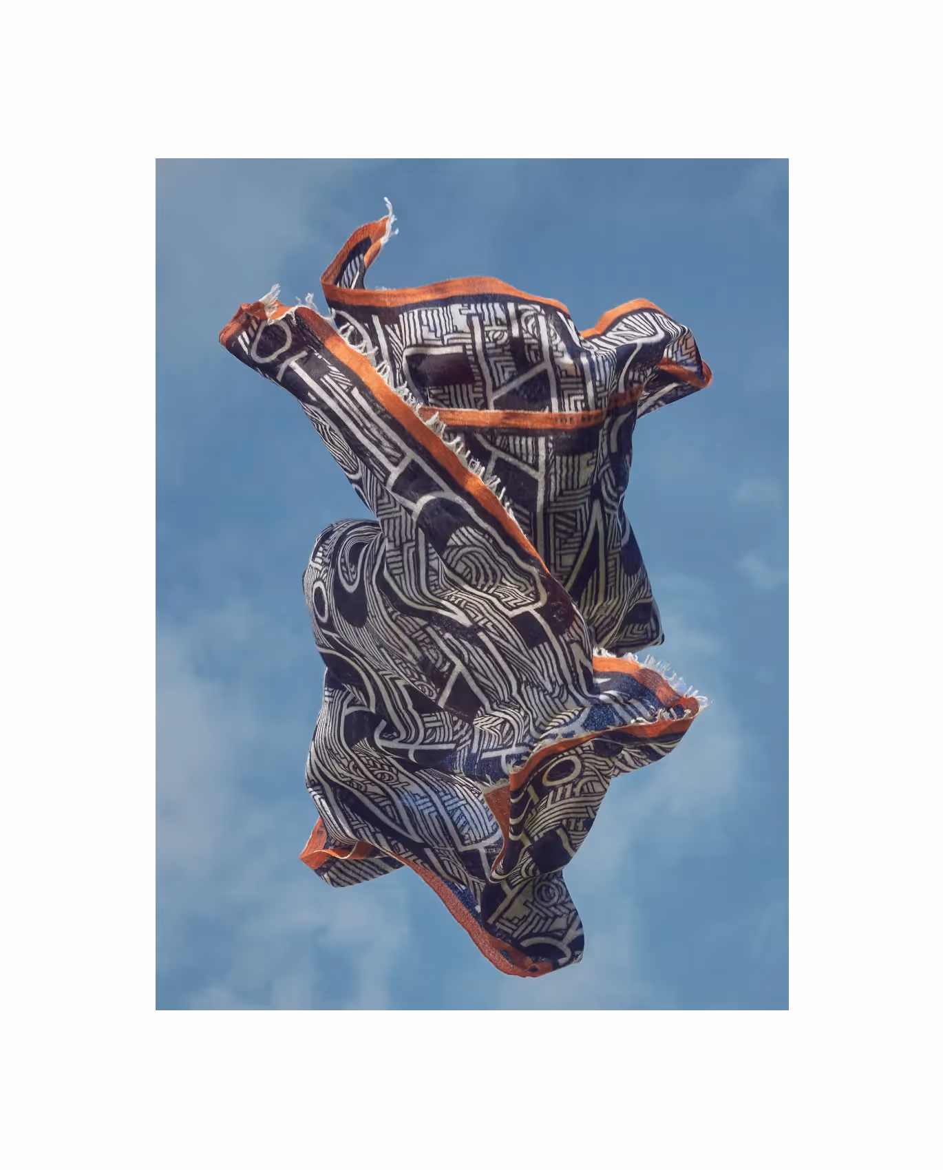 Gemustertes Tuch mit grafischem Design schwebt vor blauem Himmel