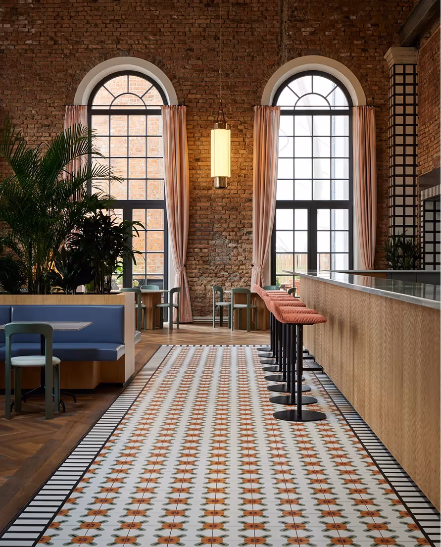 Sitzbereich mit Fliesenboden und hohen Fenstern im Restaurant