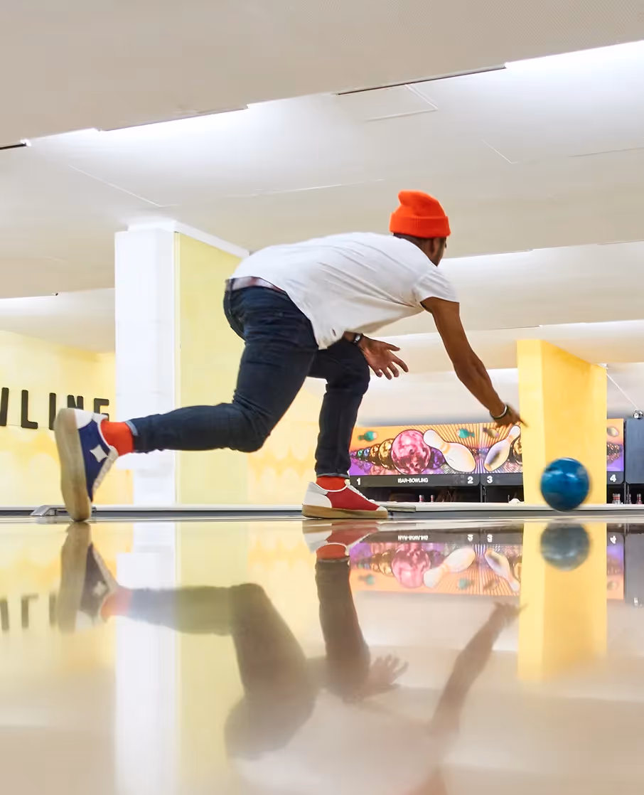 Person beim Bowlingwurf mit Sneakern auf der Bahn