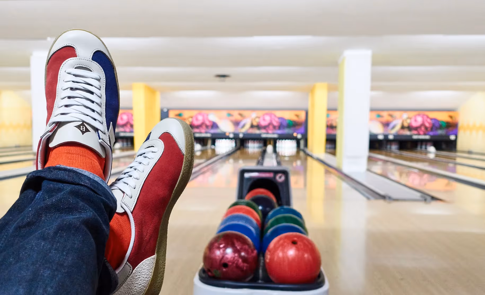 Person sitzt mit Bowlingkugel und trägt Sneaker