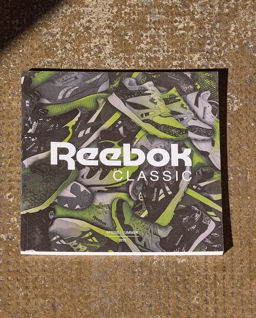 Magazin mit Sportschuh-Motiv und Logo liegt auf rauem Boden