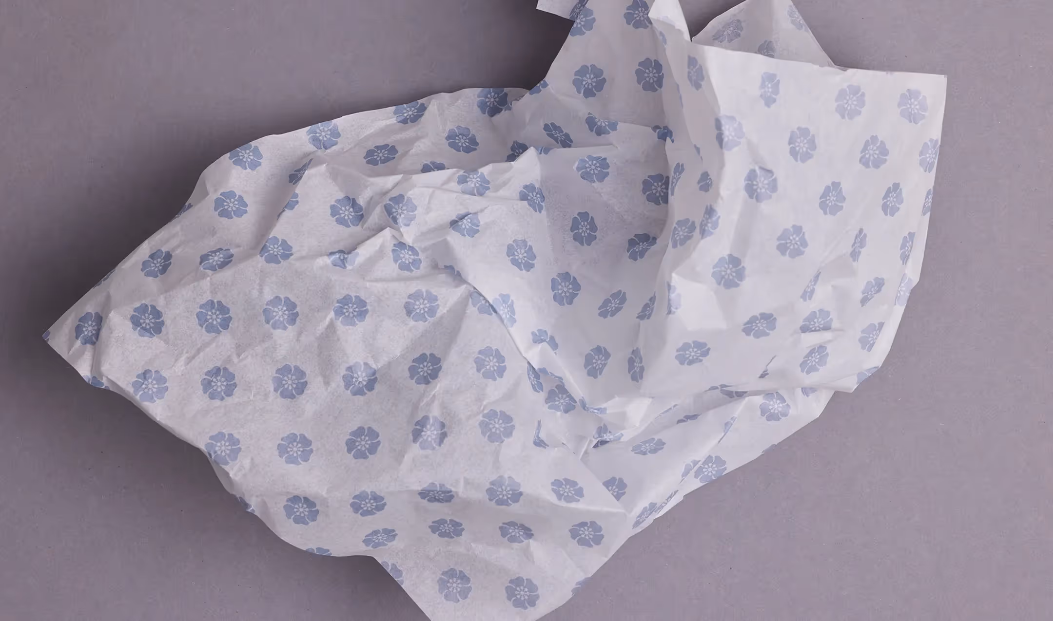 Seidenpapier mit Wadi Bildmarke (Blume) locker gefaltet auf grauem Hintergrund