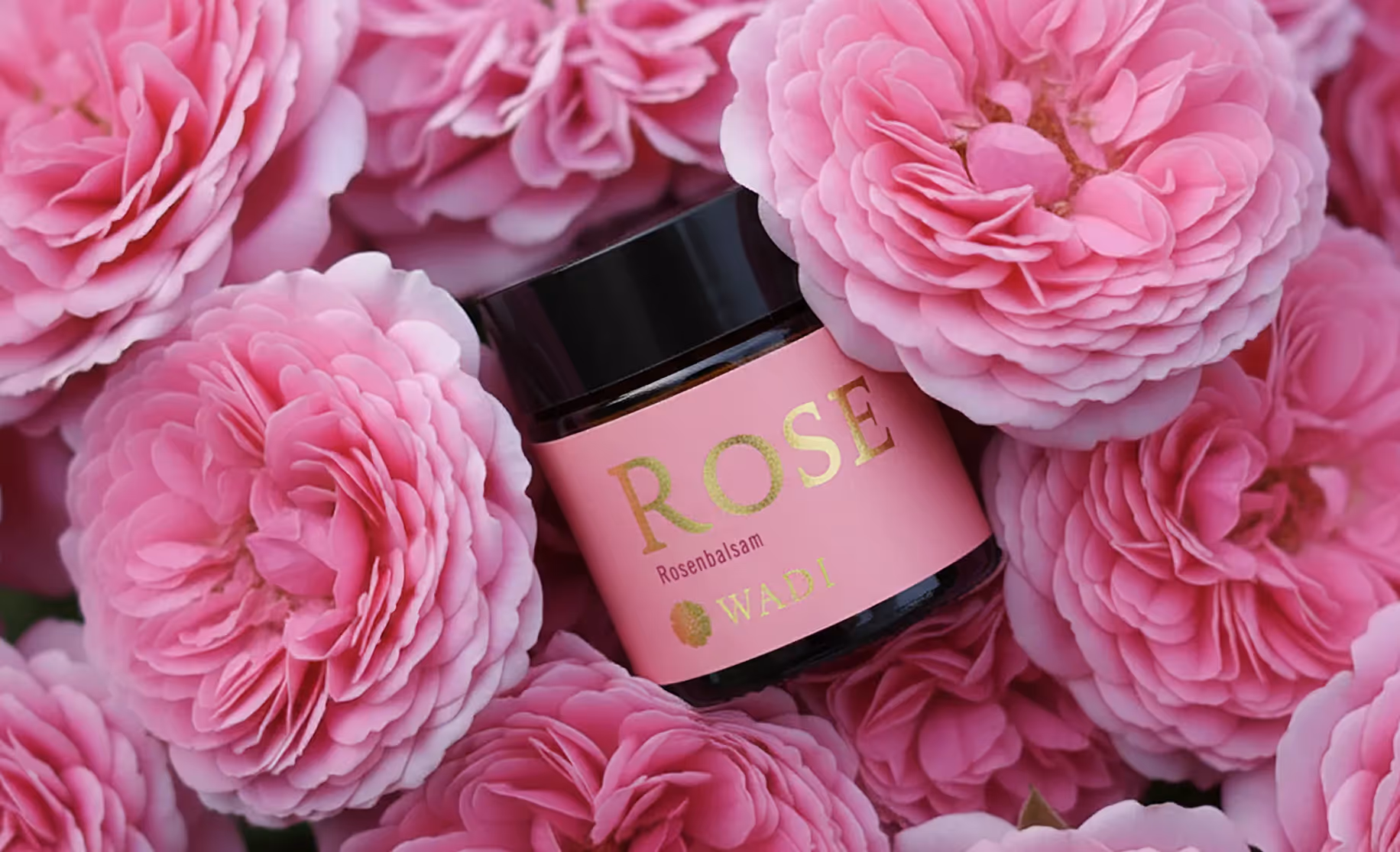 Cremebehälter zwischen rosa Blüten im WADI Produktkontext