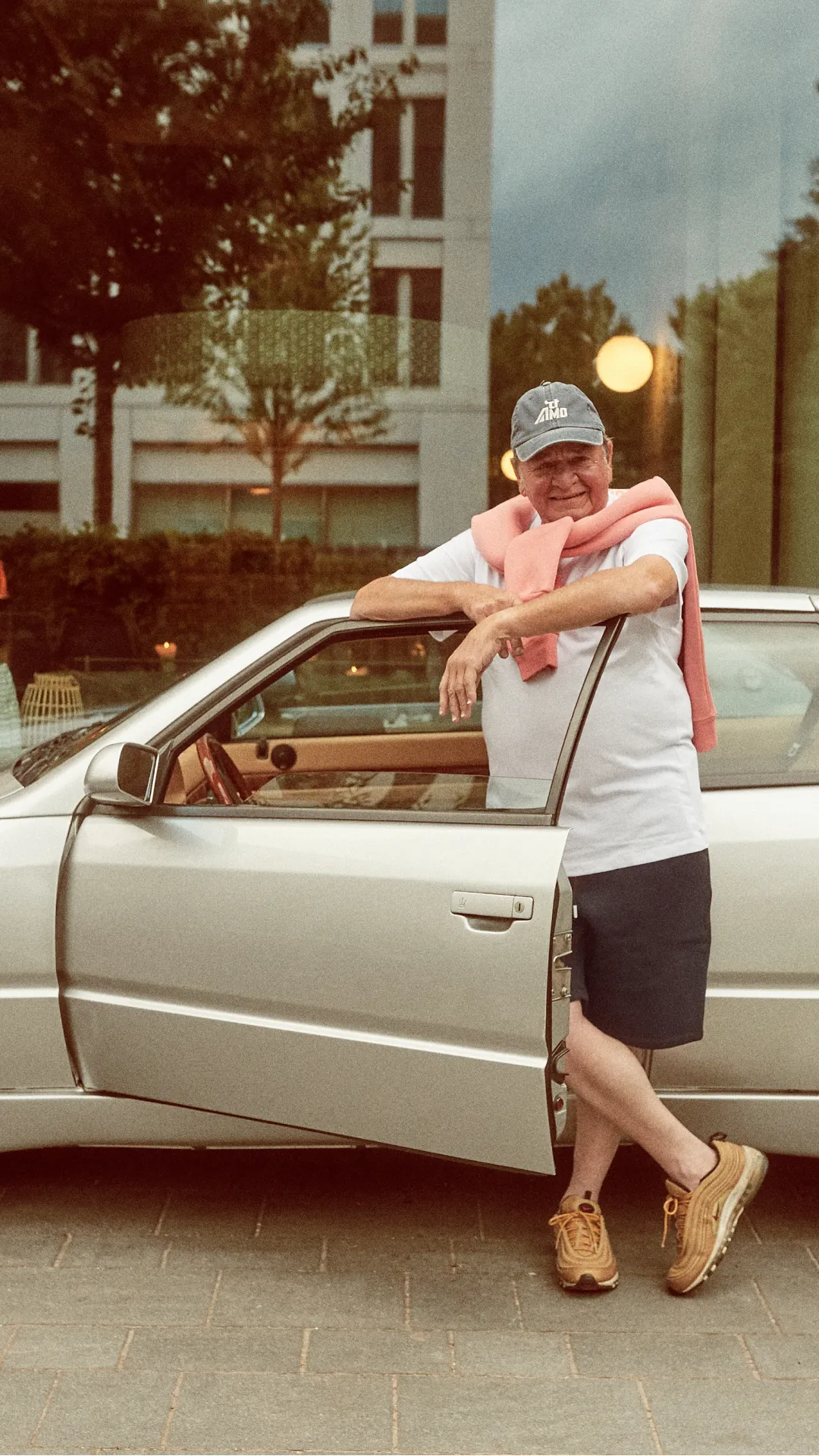 Person lehnt an einem Auto im Außenbereich